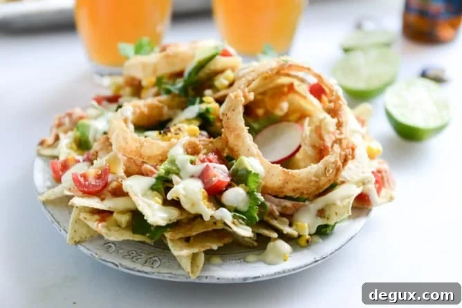 summer BBQ chicken nachos with buttermilk onion rings and white cheddar queso