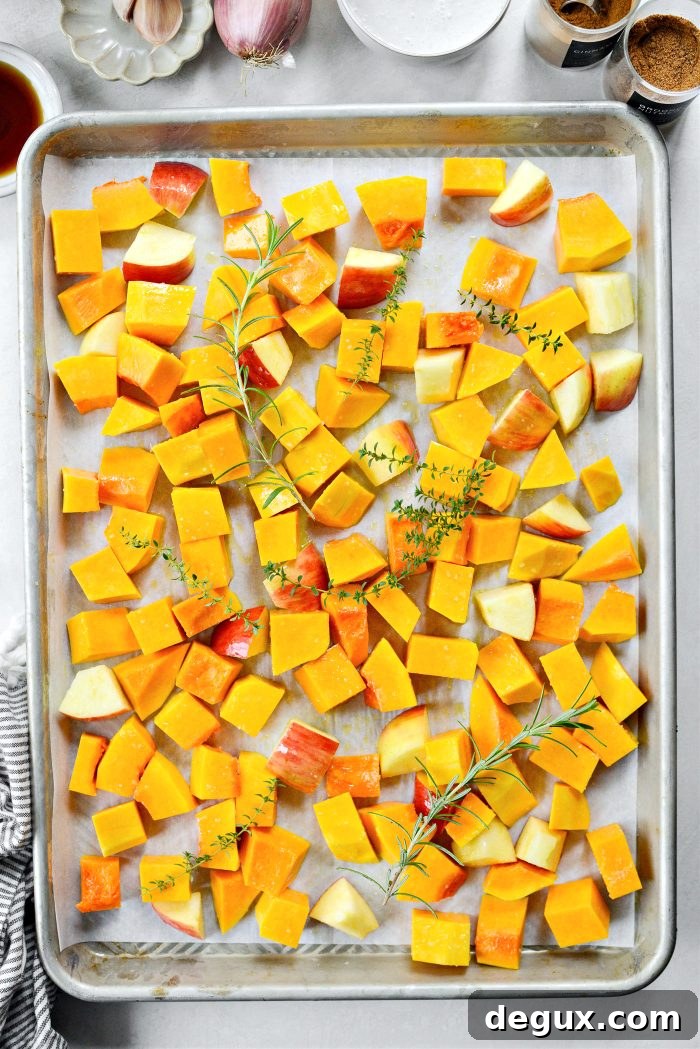 butternut squash, apples and herbs on baking sheet