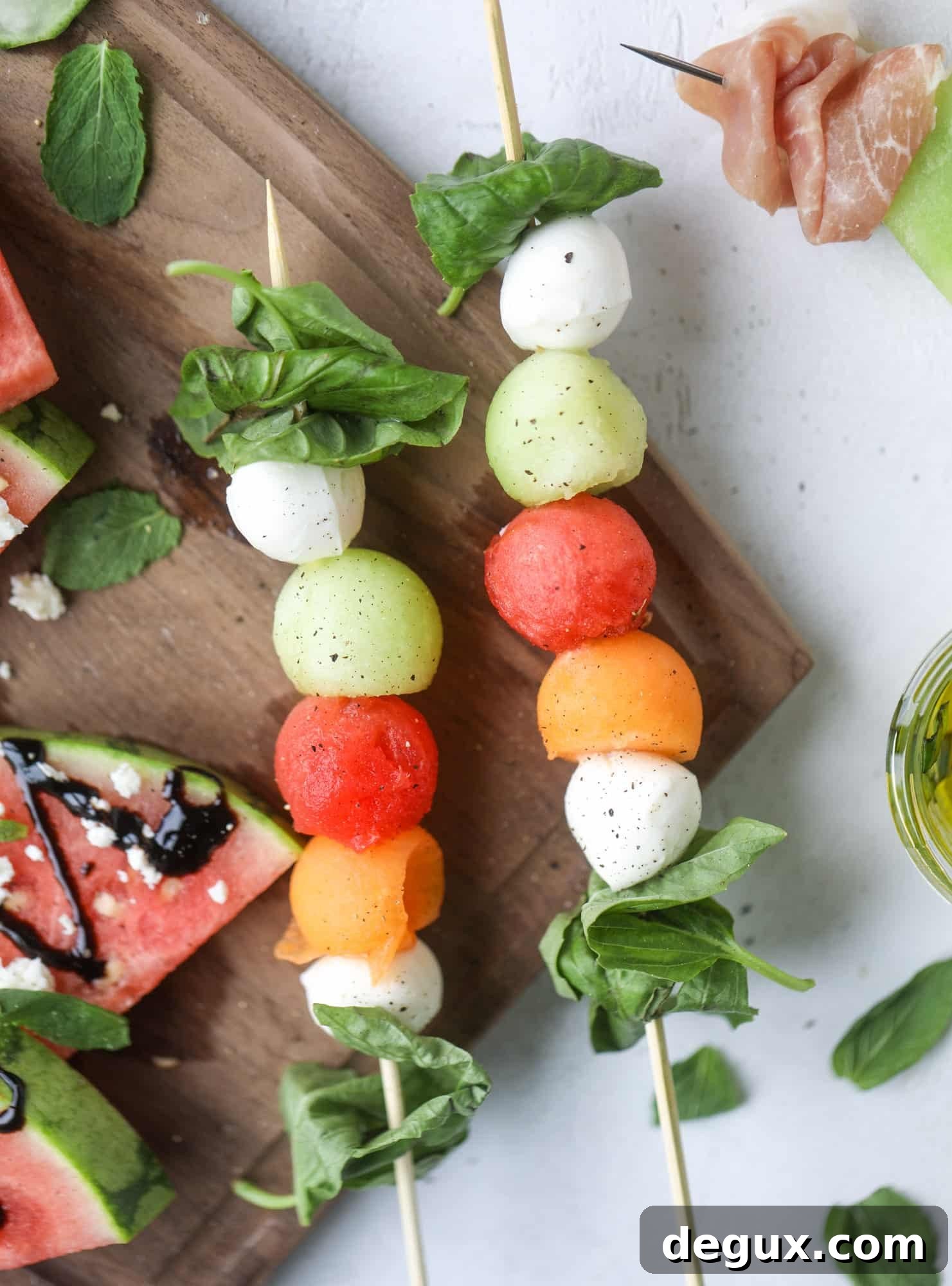 Create a melon summer snacking board with watermelon, cantaloupe, cucumber and honeydew. Drizzled with balsalmic, pesto, fresh herbs and paired with prosciutto and marinated mozzarella. I howsweeteats.com #melon #summer #snack #cheese #board #watermelon