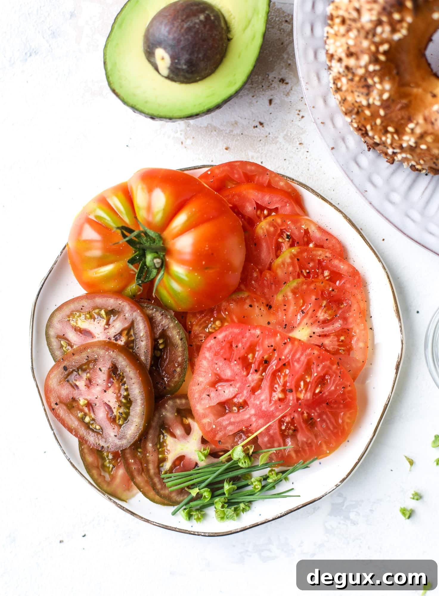 These avocado tomato sandwiches are the perfect lunch! Complete with veggie cream cheese, smoked sea salt, fresh chives and microgreens, the sliced avocado and heirloom tomatoes are sandwiched on an everything bagel for a flavor explosion. I howsweeteats.com #avocado #tomato #sandwich #healthy #lunch