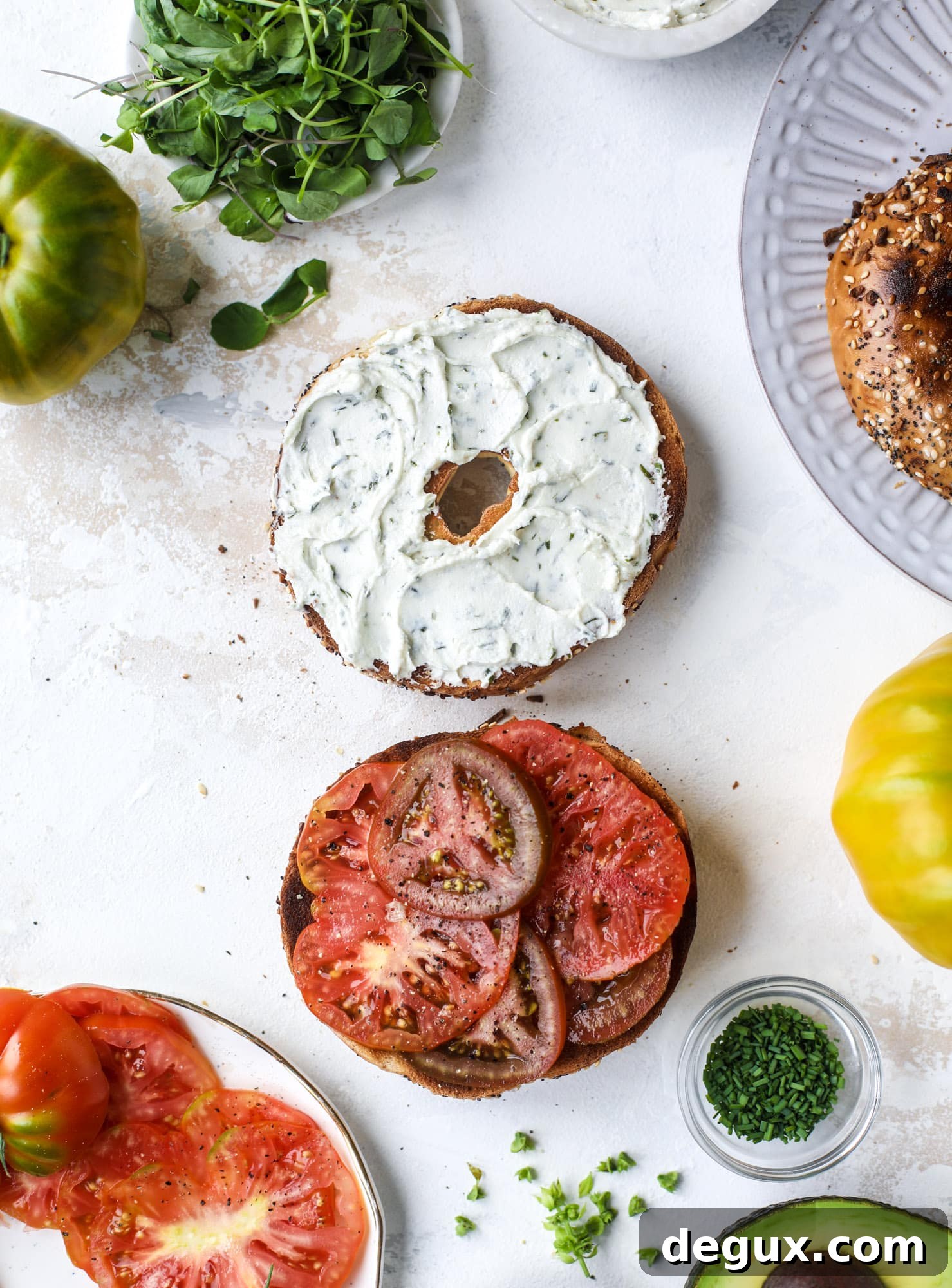 These avocado tomato sandwiches are the perfect lunch! Complete with veggie cream cheese, smoked sea salt, fresh chives and microgreens, the sliced avocado and heirloom tomatoes are sandwiched on an everything bagel for a flavor explosion. I howsweeteats.com #avocado #tomato #sandwich #healthy #lunch