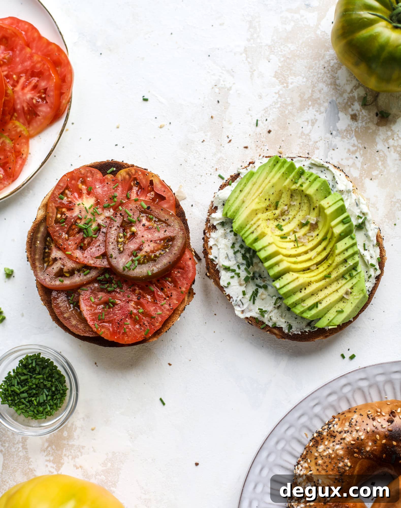 These avocado tomato sandwiches are the perfect lunch! Complete with veggie cream cheese, smoked sea salt, fresh chives and microgreens, the sliced avocado and heirloom tomatoes are sandwiched on an everything bagel for a flavor explosion. I howsweeteats.com #avocado #tomato #sandwich #healthy #lunch