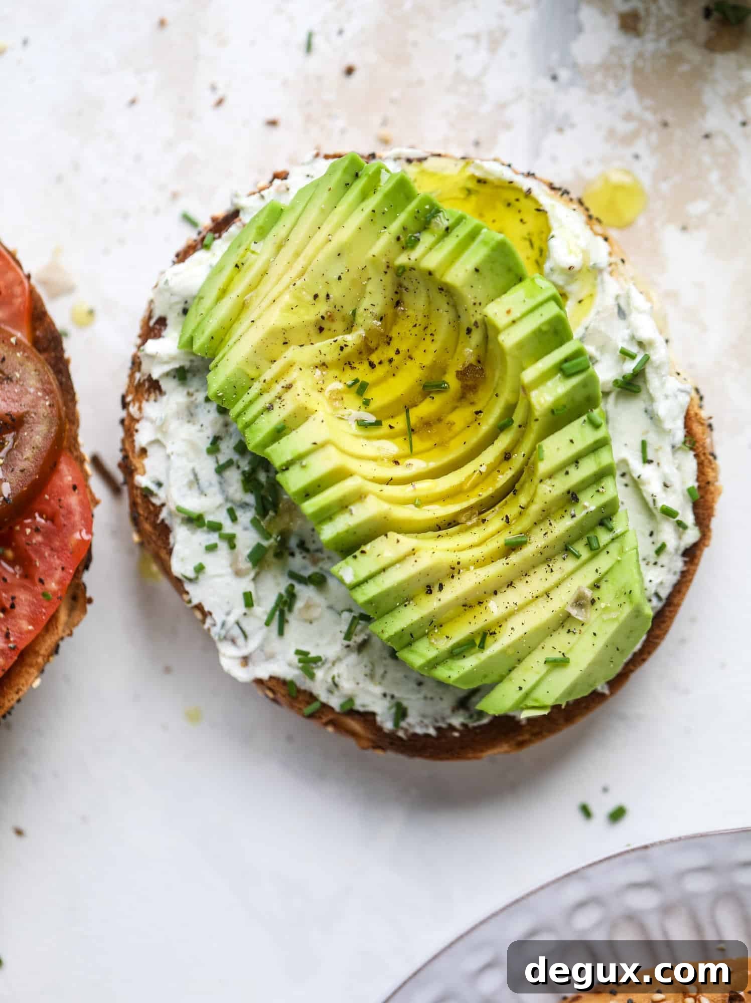 These avocado tomato sandwiches are the perfect lunch! Complete with veggie cream cheese, smoked sea salt, fresh chives and microgreens, the sliced avocado and heirloom tomatoes are sandwiched on an everything bagel for a flavor explosion. I howsweeteats.com #avocado #tomato #sandwich #healthy #lunch