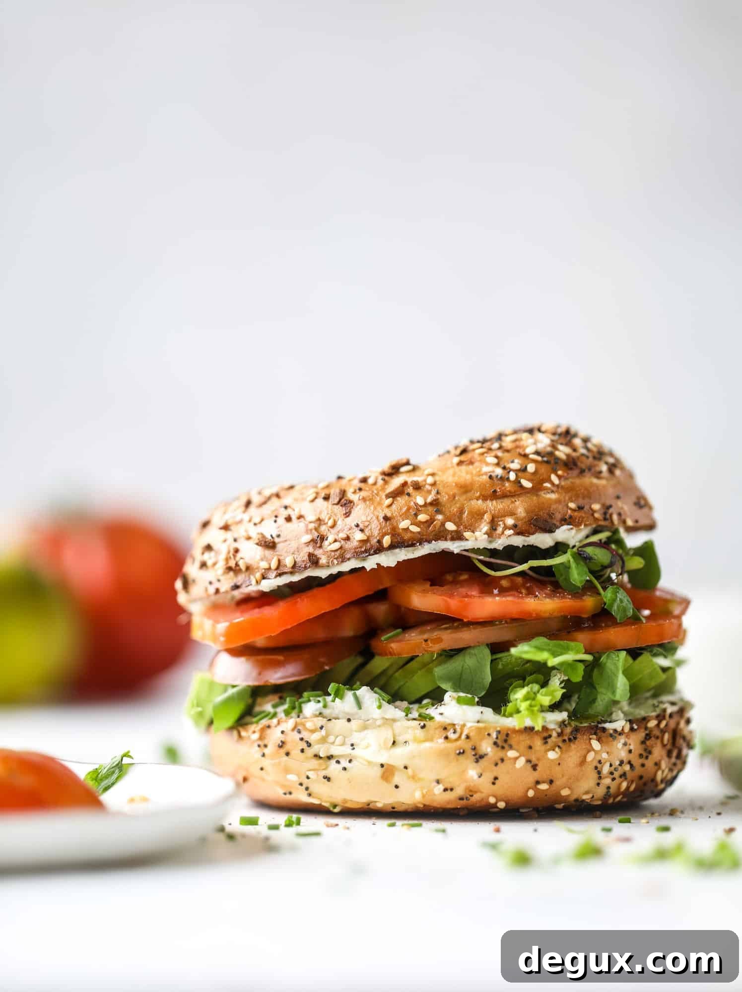 These avocado tomato sandwiches are the perfect lunch! Complete with veggie cream cheese, smoked sea salt, fresh chives and microgreens, the sliced avocado and heirloom tomatoes are sandwiched on an everything bagel for a flavor explosion. I howsweeteats.com #avocado #tomato #sandwich #healthy #lunch