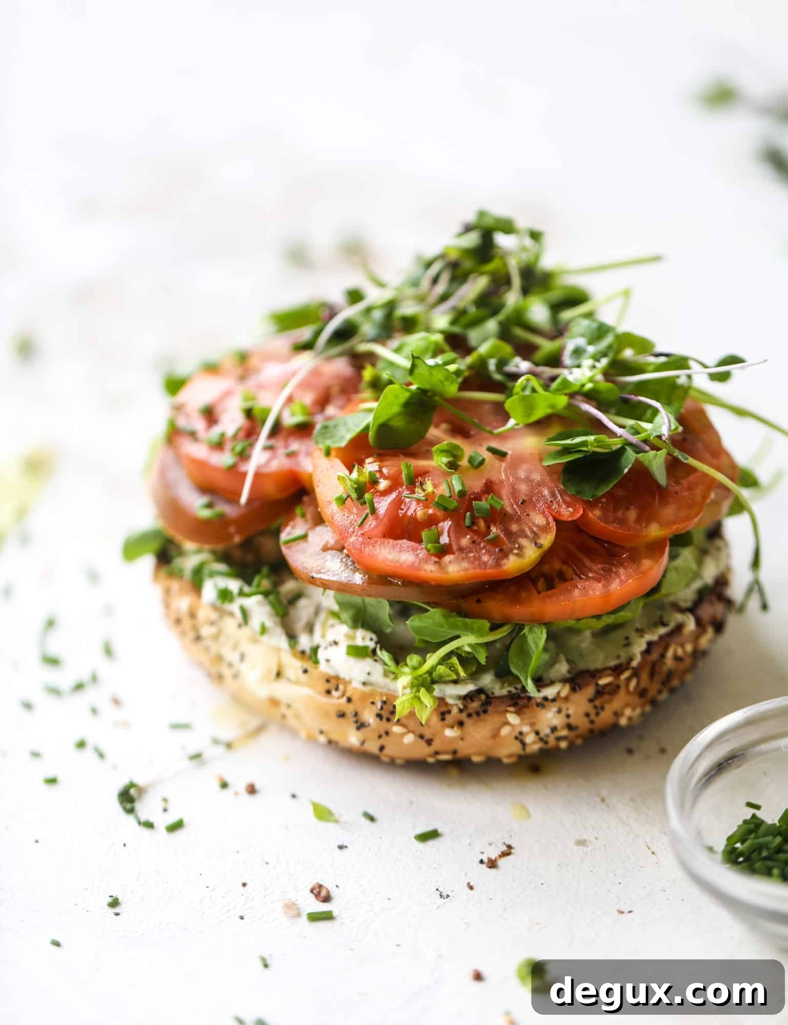 These avocado tomato sandwiches are the perfect lunch! Complete with veggie cream cheese, smoked sea salt, fresh chives and microgreens, the sliced avocado and heirloom tomatoes are sandwiched on an everything bagel for a flavor explosion. I howsweeteats.com #avocado #tomato #sandwich #healthy #lunch