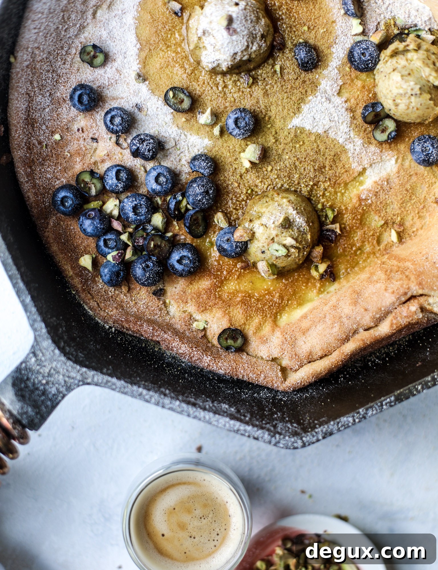 This incredible dutch baby recipe is fluffy and light and perfect for breakfast! It's sprinkled with pistachio sugar and served with pistachio butter and fresh blueberries.
