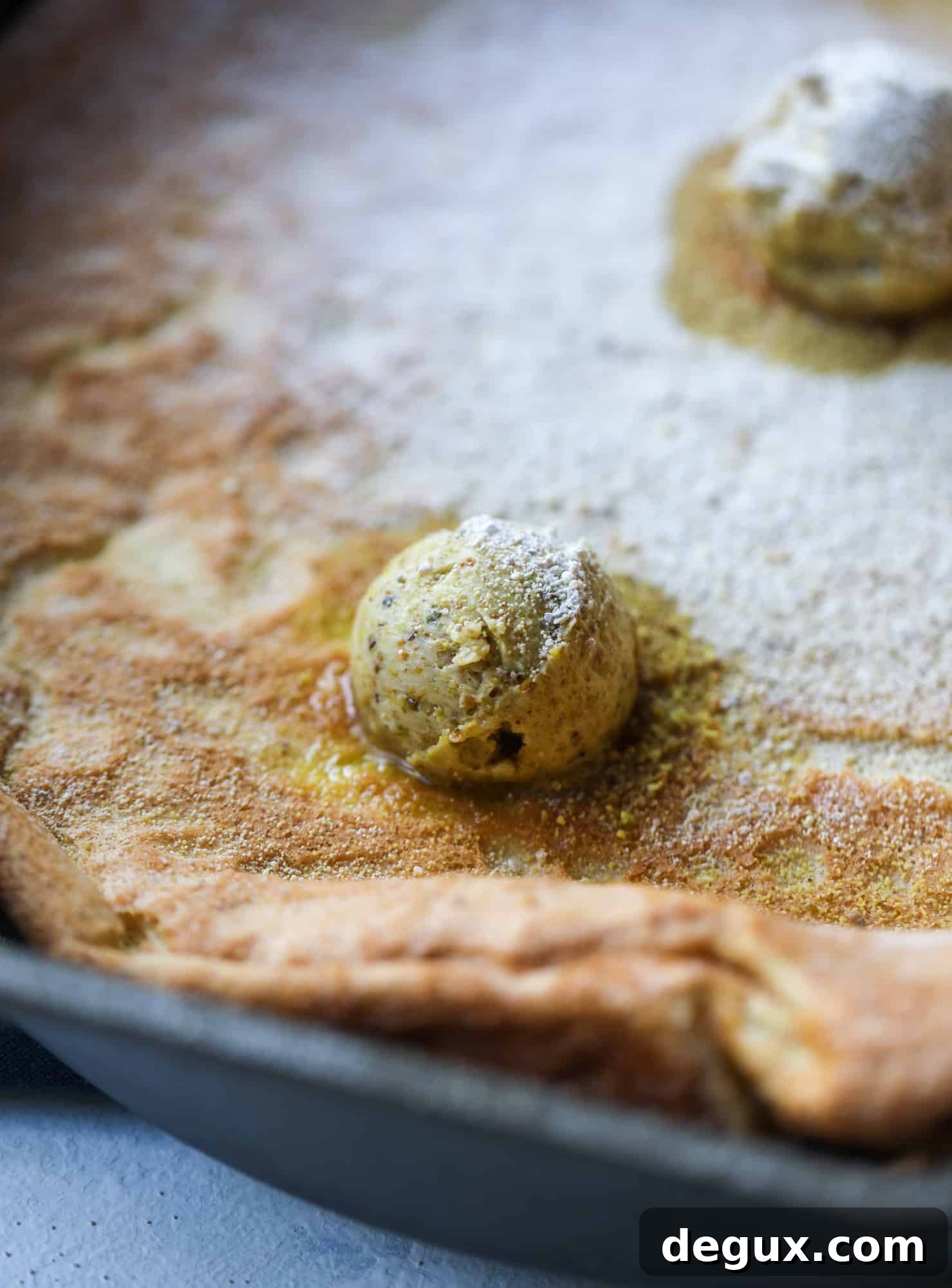 This incredible dutch baby recipe is fluffy and light and perfect for breakfast! It's sprinkled with pistachio sugar and served with pistachio butter and fresh blueberries.