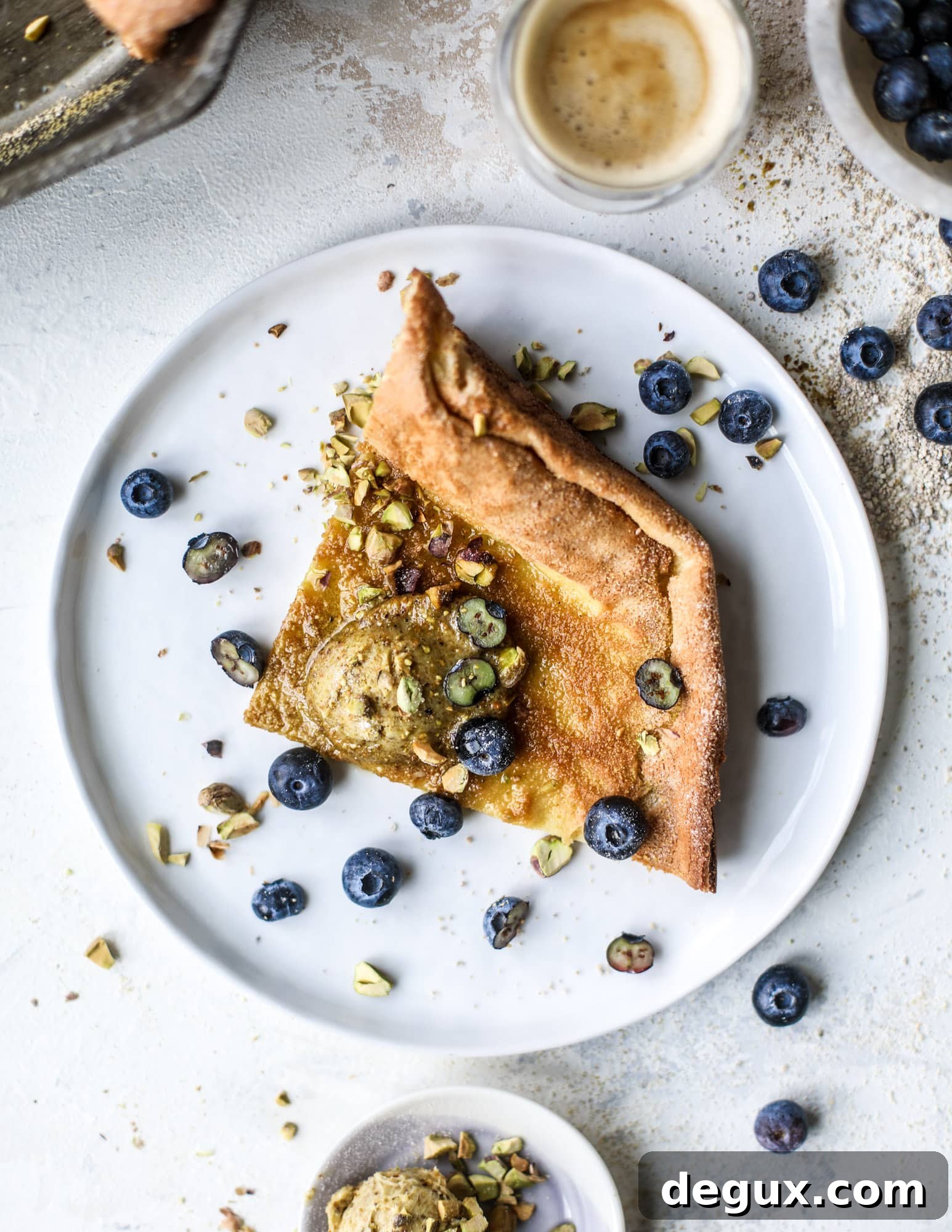This incredible dutch baby recipe is fluffy and light and perfect for breakfast! It's sprinkled with pistachio sugar and served with pistachio butter and fresh blueberries.