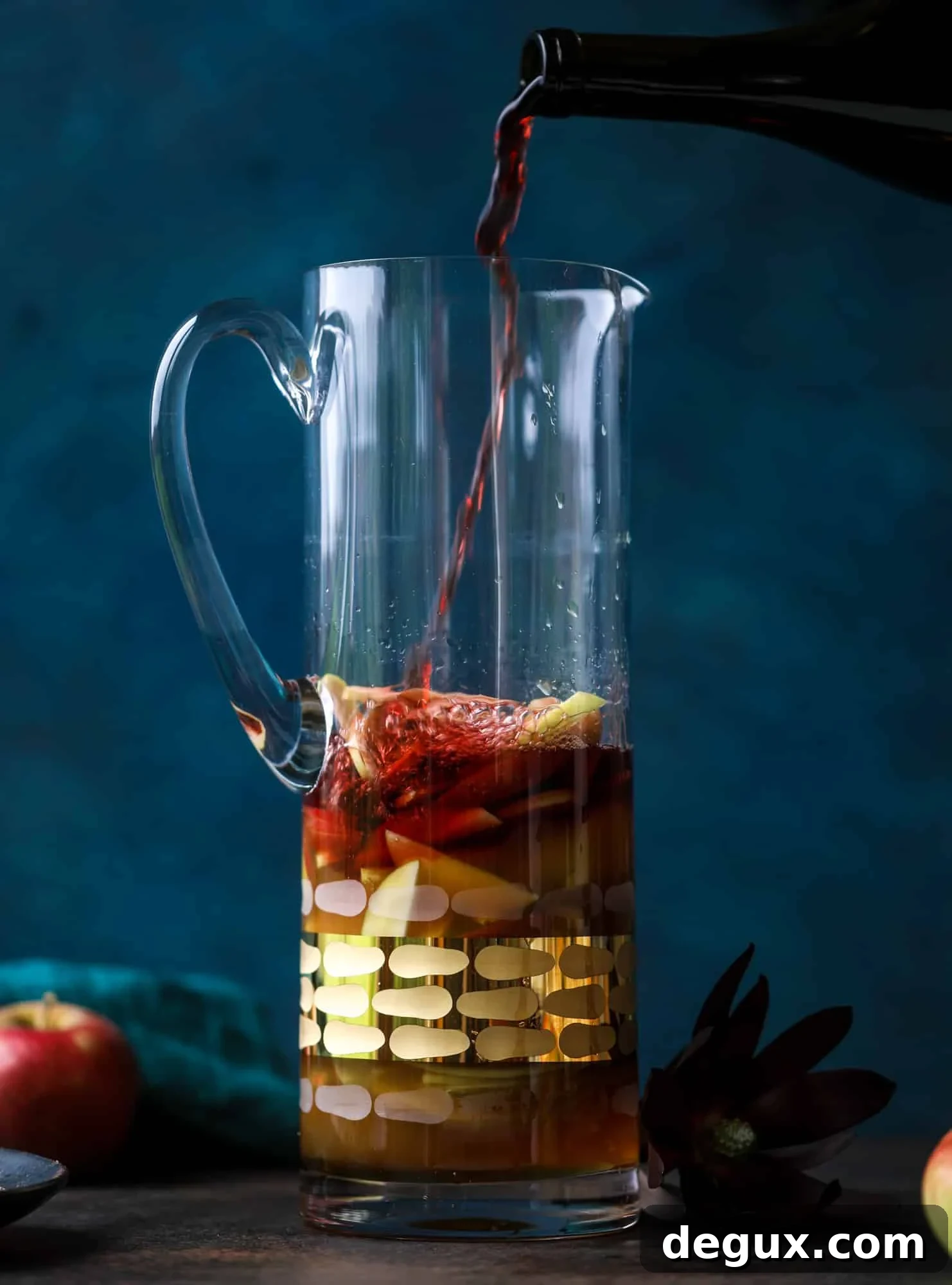 Pitcher of red apple cider sangria with apples and cinnamon.