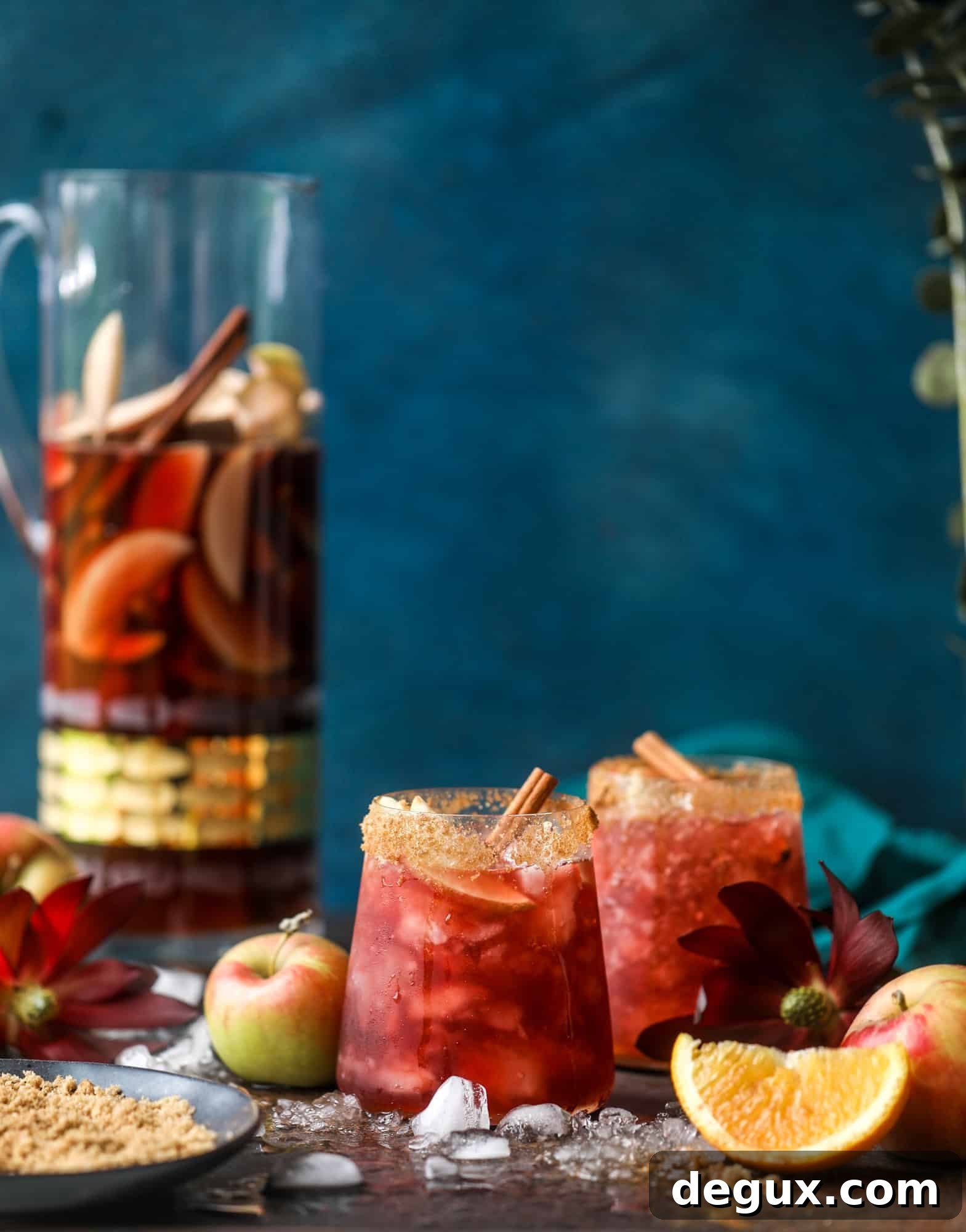 Pitcher filled with red sangria, apples, and cinnamon sticks.