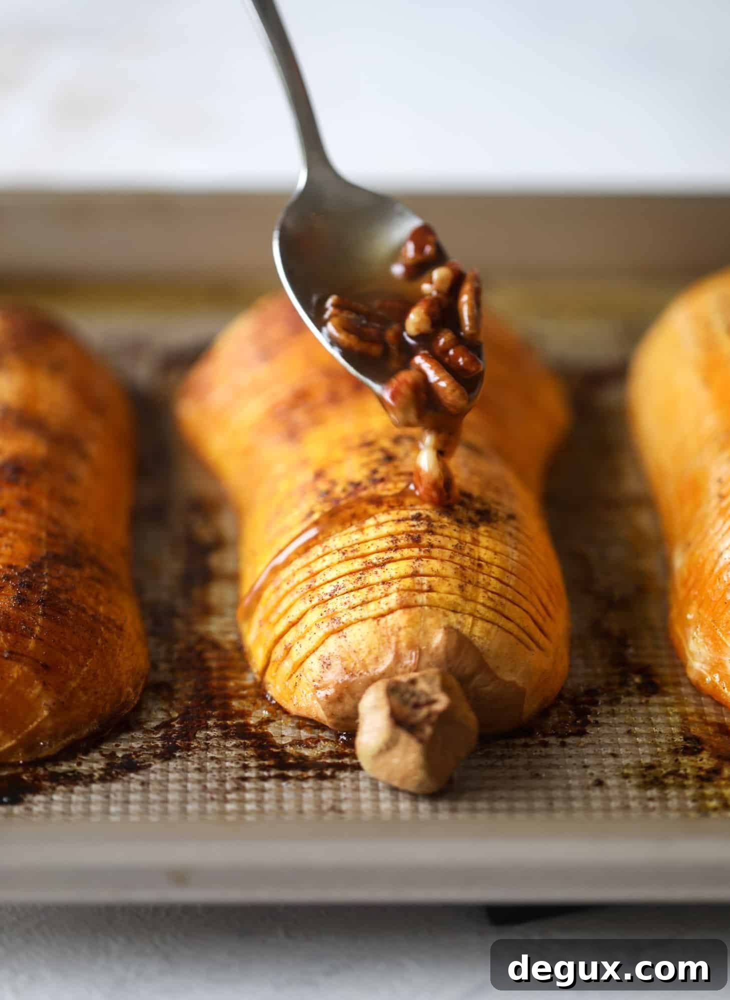 A baked hasselback butternut squash glazed with maple and topped with pecans.