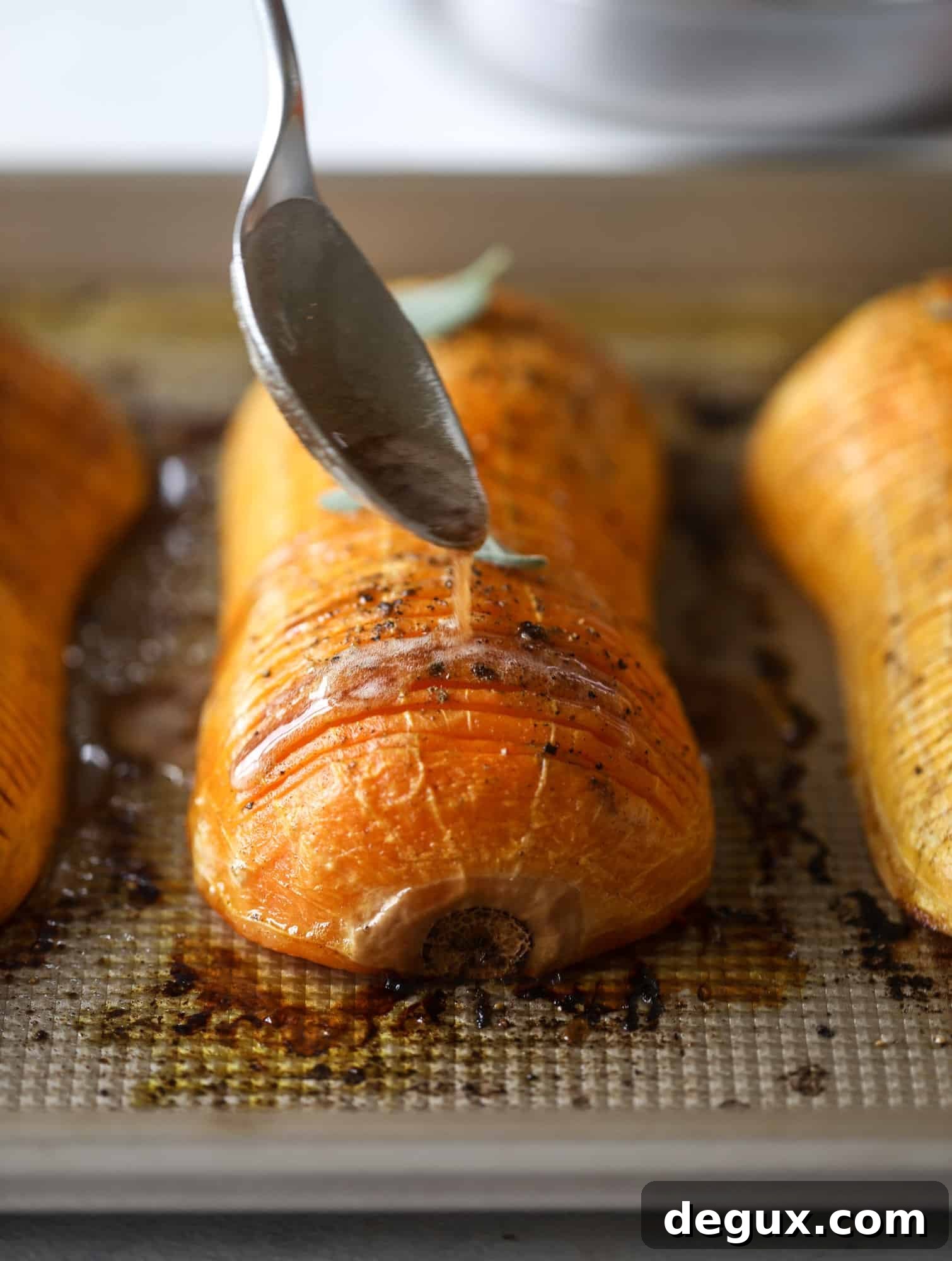 Sliced hasselback squash with maple syrup and pecans ready to be roasted.