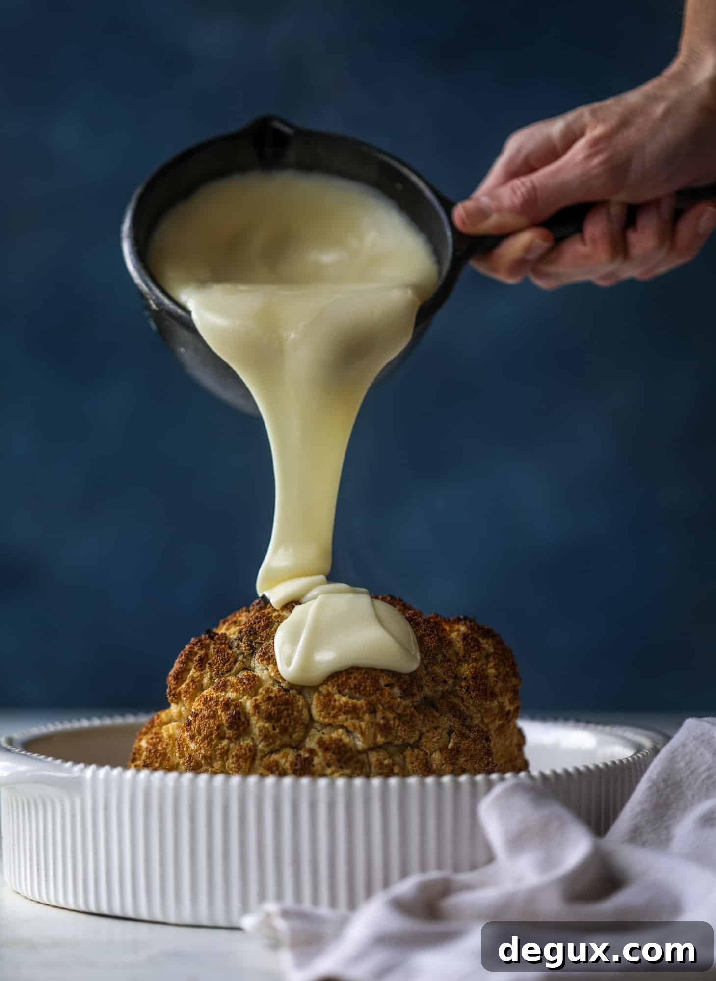 This whole roasted cauliflower fondue is roasted to toasty perfection and then covered in a fondue cheese sauce! Sprinkled with a festive garnish, it's the perfect appetizer or side dish for your dinner party, weeknight meal or movie night! I howsweeteats.com #wholeroasted #cauliflower