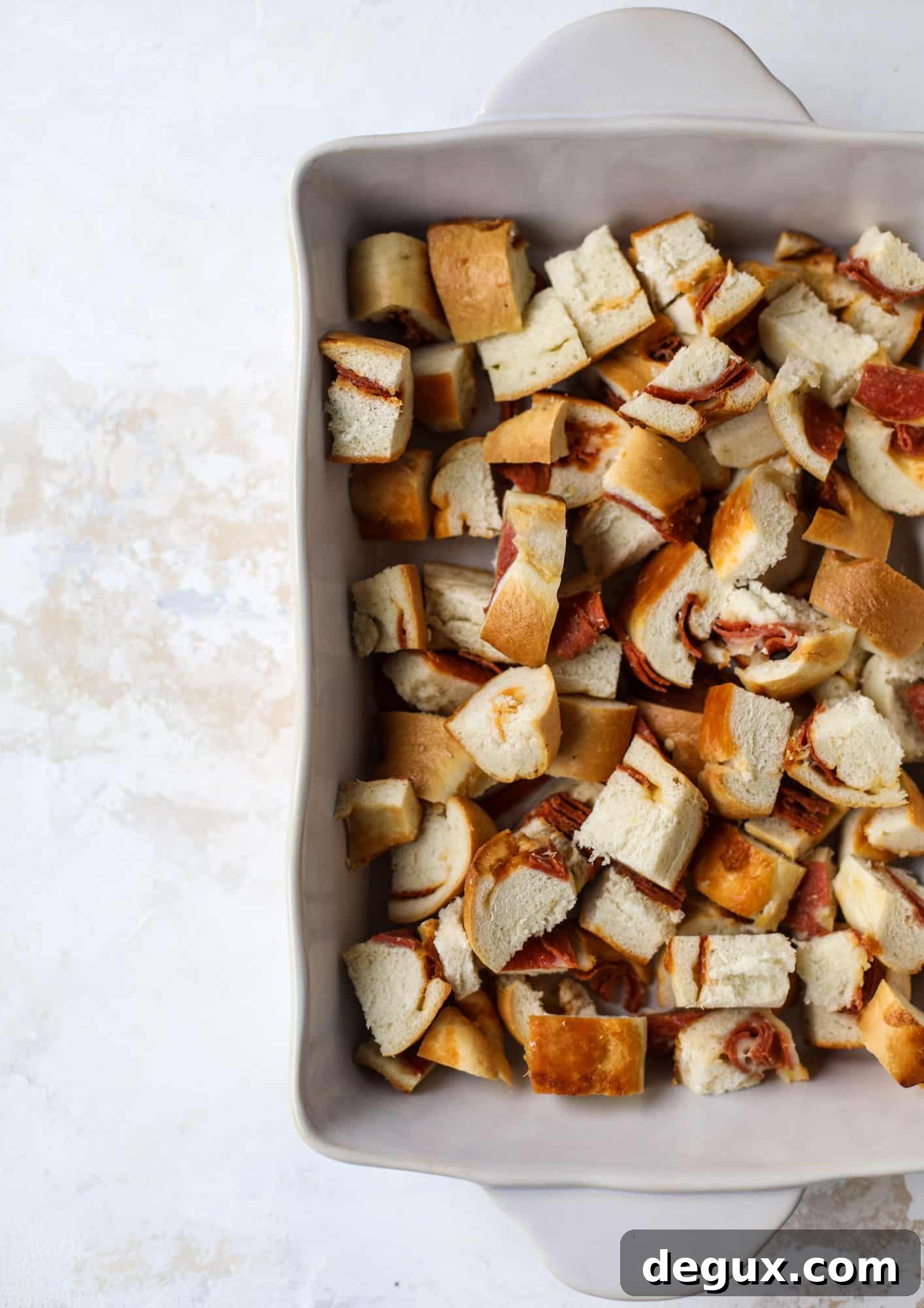 This breakfast strata is super special because the base is built on pepperoni rolls! This make ahead casserole is perfect for holiday brunches or parties and tastes like a supreme pizza. It's so easy to throw together too! I howsweeteats.com #breakfast #strata