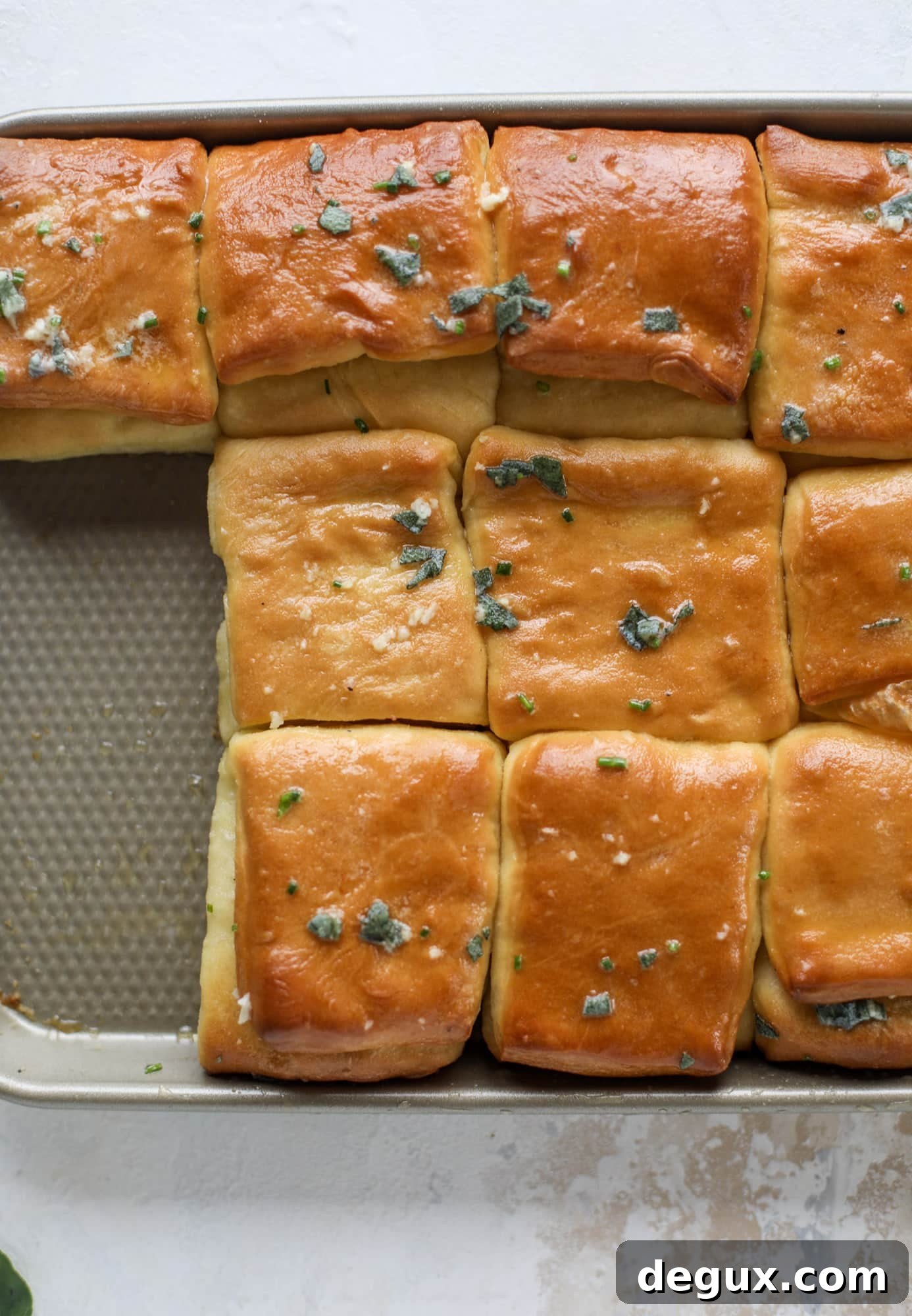 Garlic herb parker house rolls are full of incredibly buttery flavor! They are brushed with a garlic herb butter and are super fluffy, soft and tender. Perfect for Thanksgiving or the holidays and you can make the dough a bit ahead of time! I howsweeteats.com #parkerhouse #rolls