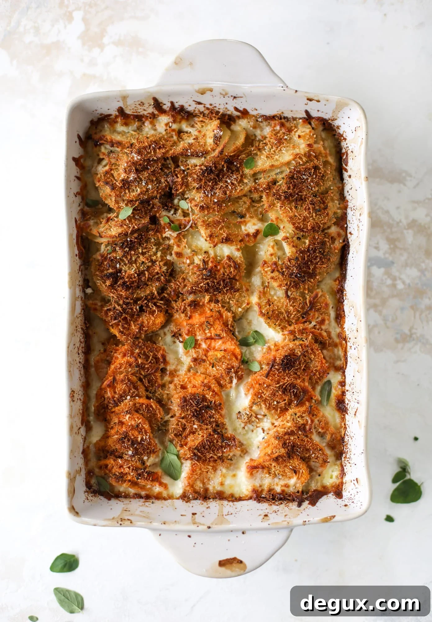 These scalloped potatoes are a cheese lover's dream. Sharp asiago and cream envelops idaho and sweet potatoes in these scalloped potatoes to please everyone! The crunchy asiago topping is irresistible. I howsweeteats.com #scalloped #potatoes