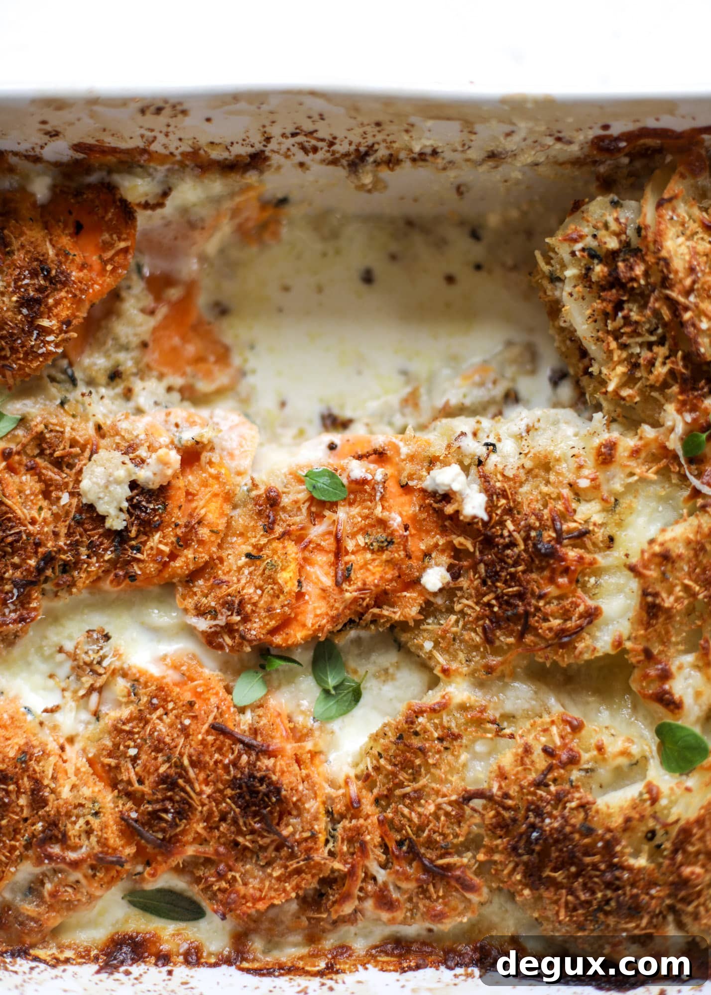These scalloped potatoes are a cheese lover's dream. Sharp asiago and cream envelops idaho and sweet potatoes in these scalloped potatoes to please everyone! The crunchy asiago topping is irresistible. I howsweeteats.com #scalloped #potatoes