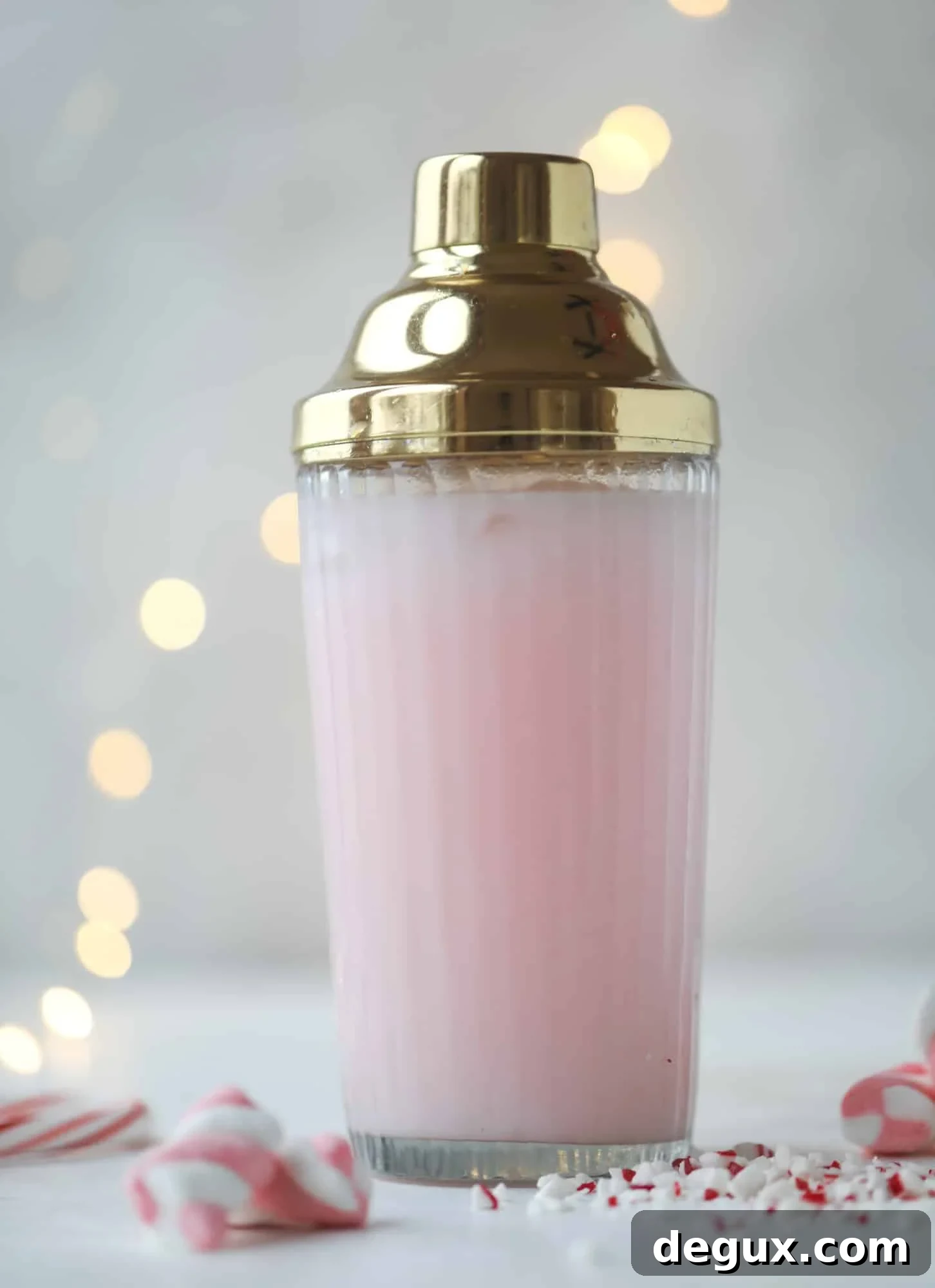 This pink peppermint cocktail is full of holiday cheer! Candy cane vodka, creme de cacao, vanilla and a drop of cream come together to create the perfect iced holiday drink that tastes like a treat! I howsweeteats.com #pinkpeppermint #cocktail