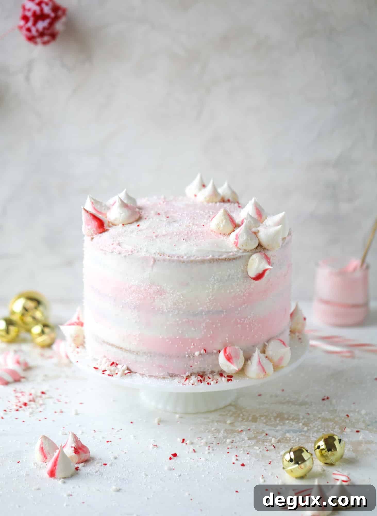 This pink peppermint cake is festive and delicious for the holidays! Layers of vanilla cake frosting with peppermint cream cheese frosting, covered in sparkly sugar and peppermint meringues. Couldn't be cuter! I #pinkpeppermint #cake