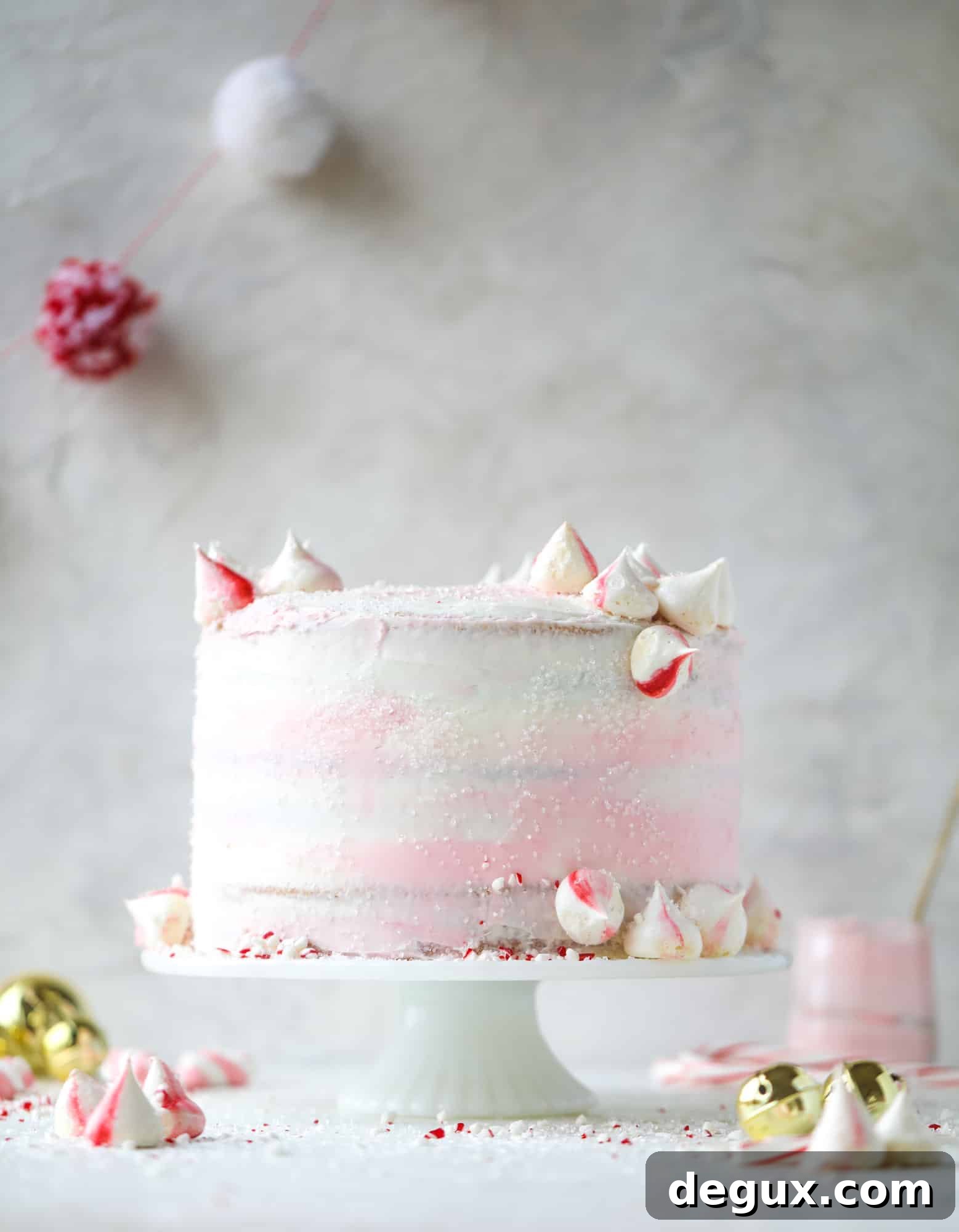 This pink peppermint cake is festive and delicious for the holidays! Layers of vanilla cake frosting with peppermint cream cheese frosting, covered in sparkly sugar and peppermint meringues. Couldn't be cuter! I #pinkpeppermint #cake