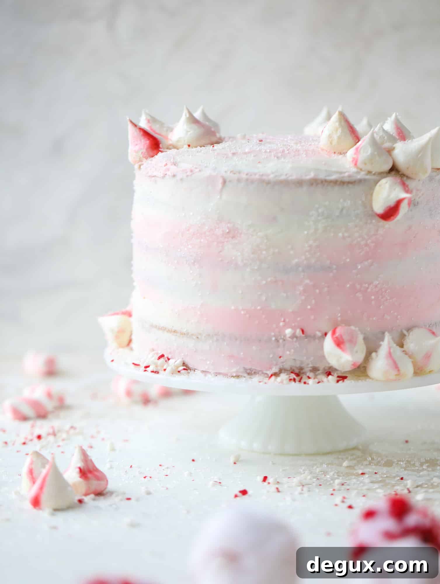 This pink peppermint cake is festive and delicious for the holidays! Layers of vanilla cake frosting with peppermint cream cheese frosting, covered in sparkly sugar and peppermint meringues. Couldn't be cuter! I #pinkpeppermint #cake