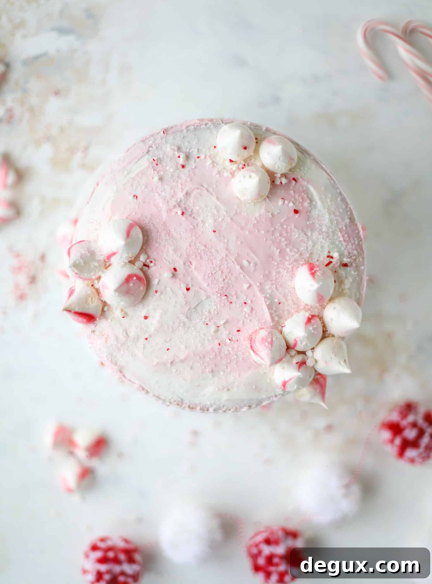 This pink peppermint cake is festive and delicious for the holidays! Layers of vanilla cake frosting with peppermint cream cheese frosting, covered in sparkly sugar and peppermint meringues. Couldn't be cuter! I #pinkpeppermint #cake