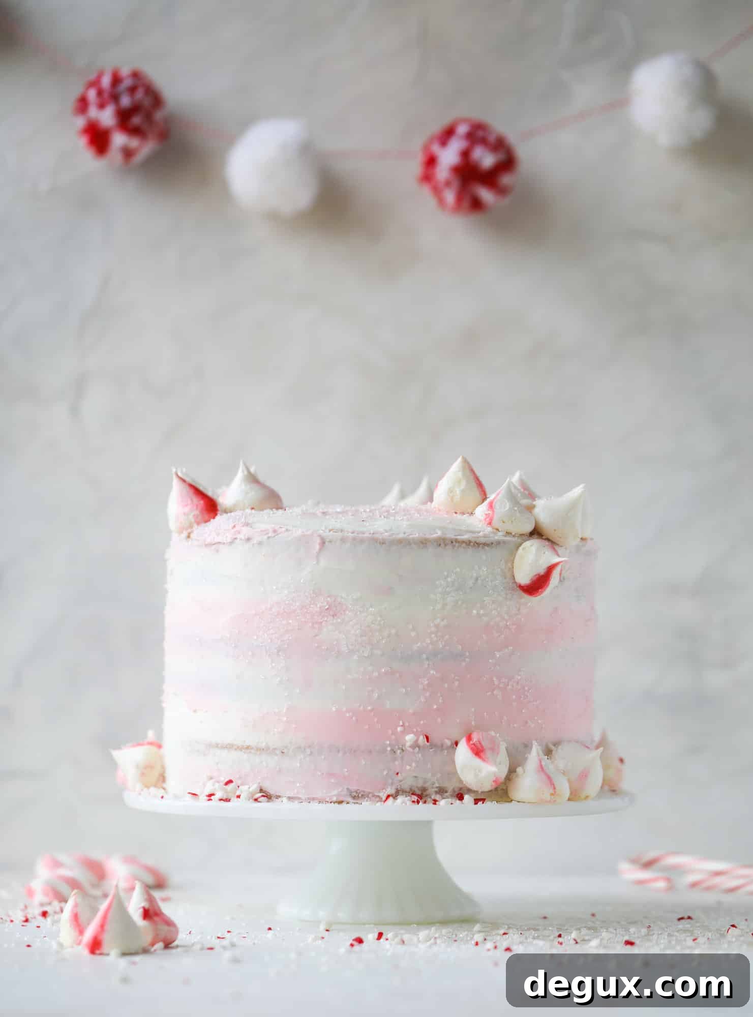 This pink peppermint cake is festive and delicious for the holidays! Layers of vanilla cake frosting with peppermint cream cheese frosting, covered in sparkly sugar and peppermint meringues. Couldn't be cuter! I #pinkpeppermint #cake