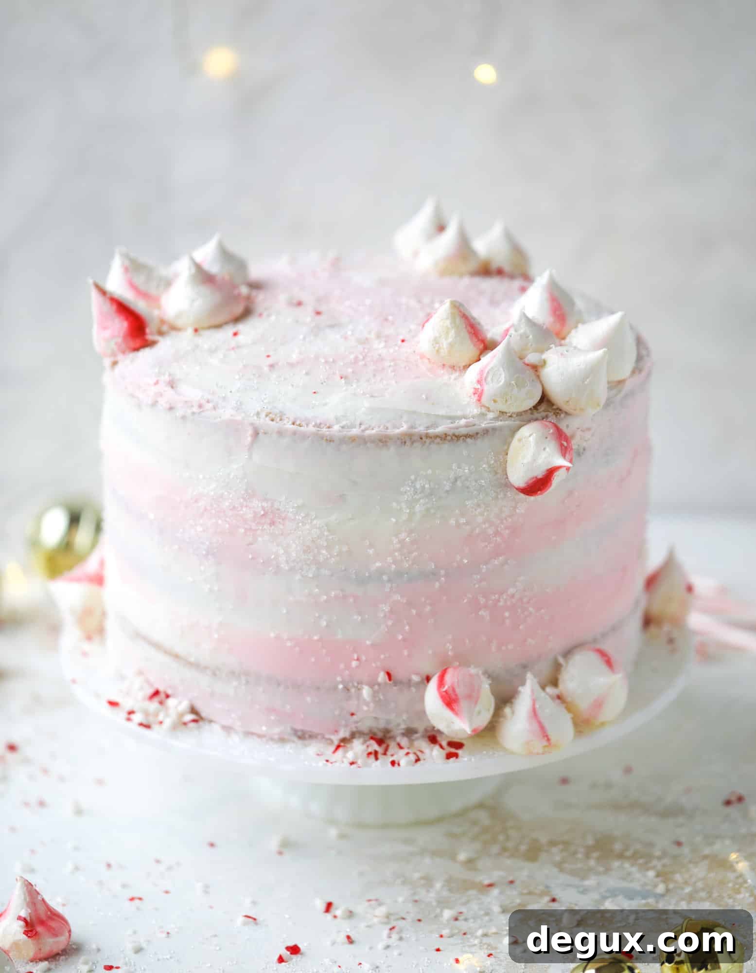 This pink peppermint cake is festive and delicious for the holidays! Layers of vanilla cake frosting with peppermint cream cheese frosting, covered in sparkly sugar and peppermint meringues. Couldn't be cuter! I #pinkpeppermint #cake
