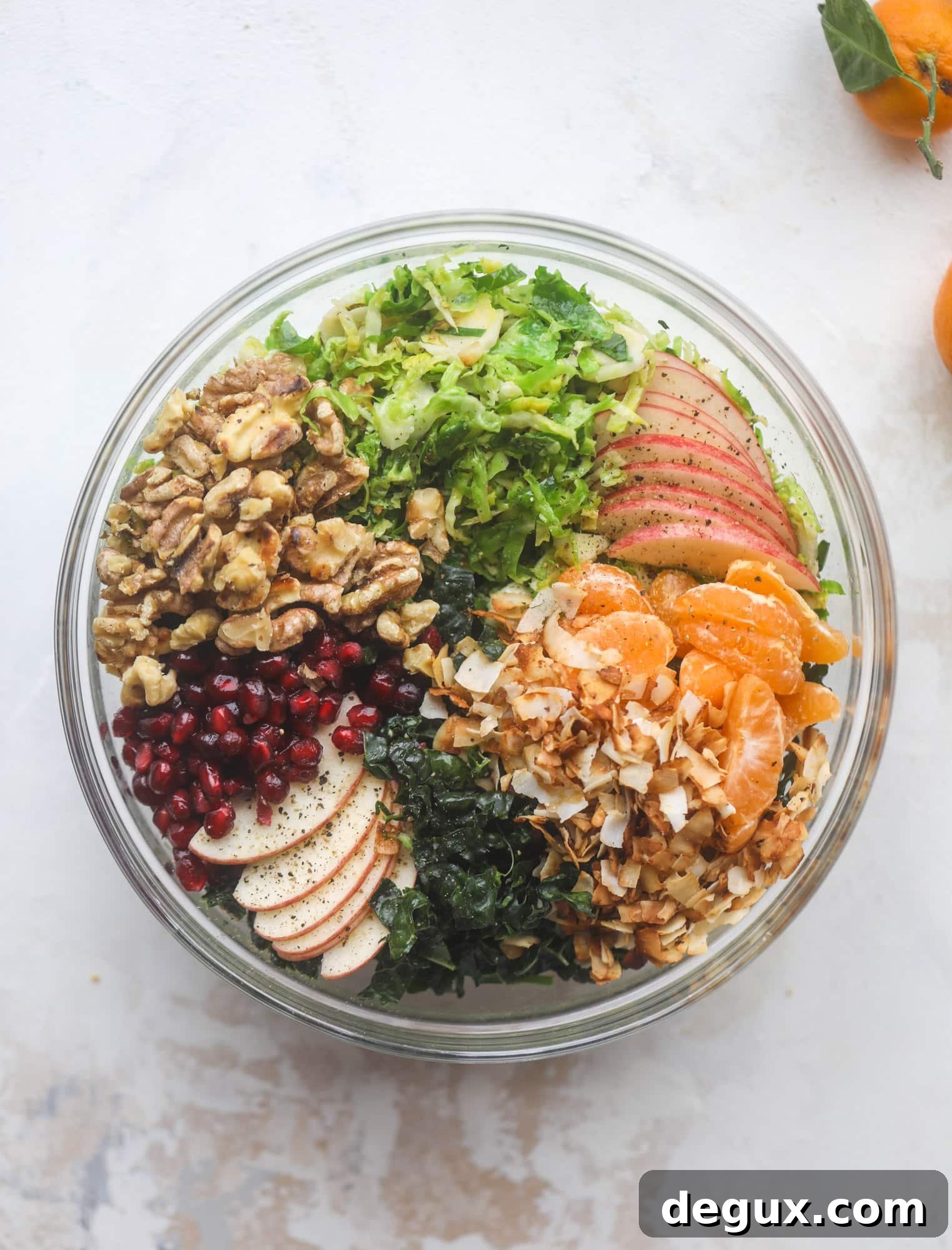 This winter crunch salad is loaded with tons of delicious, crunchy seasonal ingredients. A base of brussels sprouts and kale is topped with sliced apples, satsuma wedges, pomegranate arils, toasted walnuts and savory flaked coconut crunch. Delish! I howsweeteats.com #winter #salad