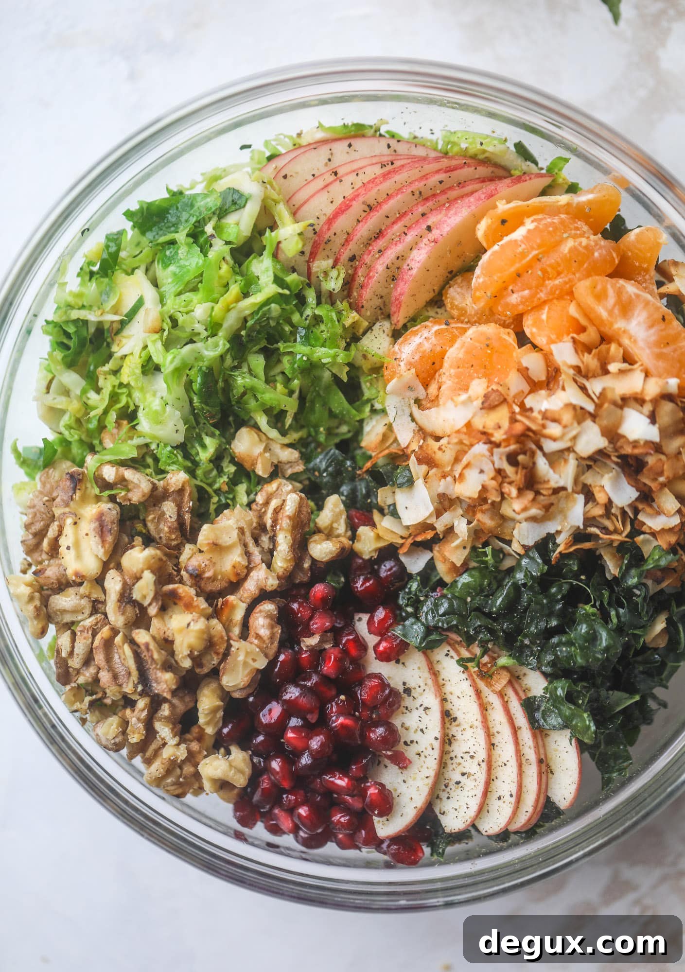 This winter crunch salad is loaded with tons of delicious, crunchy seasonal ingredients. A base of brussels sprouts and kale is topped with sliced apples, satsuma wedges, pomegranate arils, toasted walnuts and savory flaked coconut crunch. Delish! I howsweeteats.com #winter #salad
