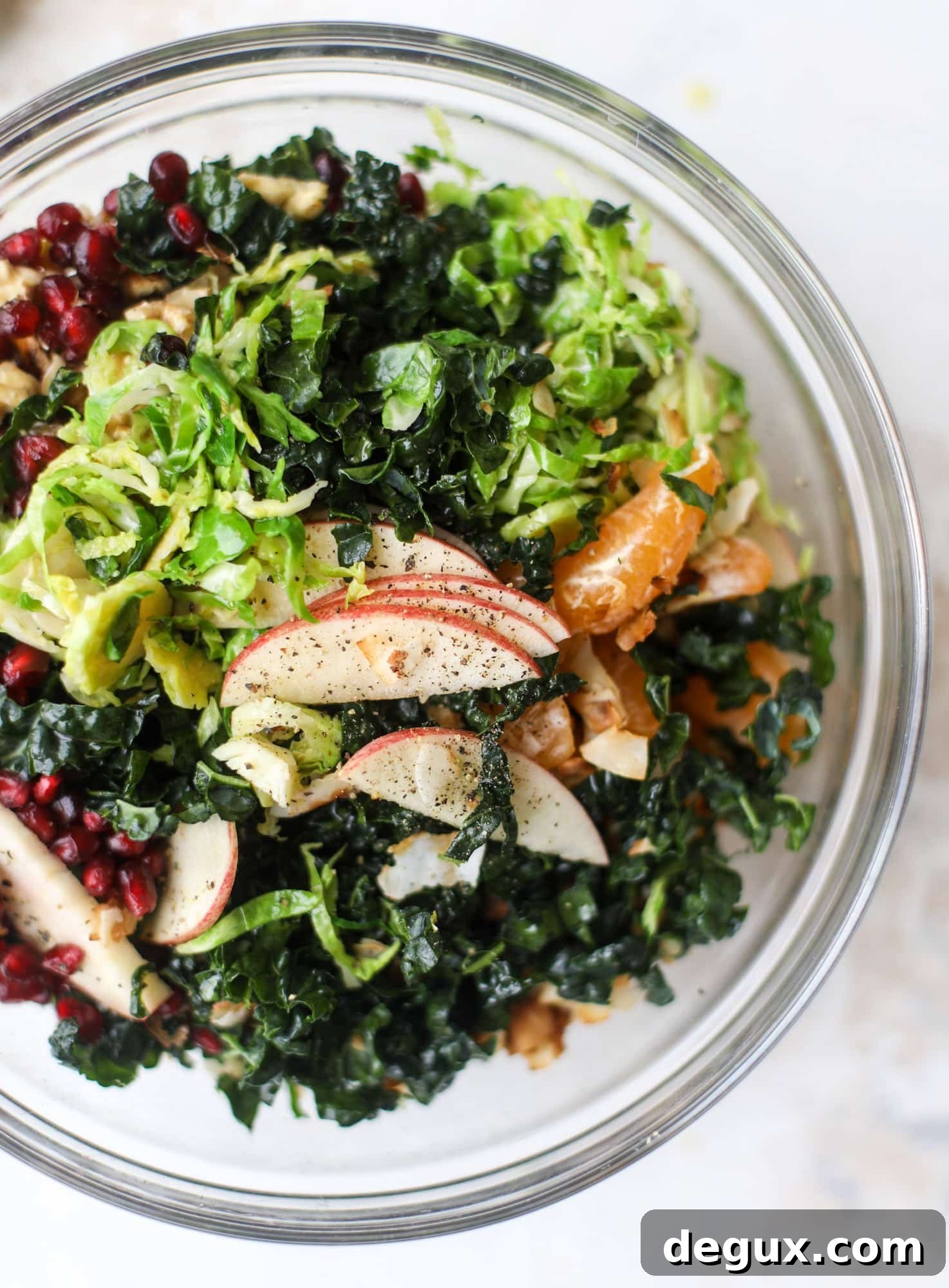 This winter crunch salad is loaded with tons of delicious, crunchy seasonal ingredients. A base of brussels sprouts and kale is topped with sliced apples, satsuma wedges, pomegranate arils, toasted walnuts and savory flaked coconut crunch. Delish! I howsweeteats.com #winter #salad