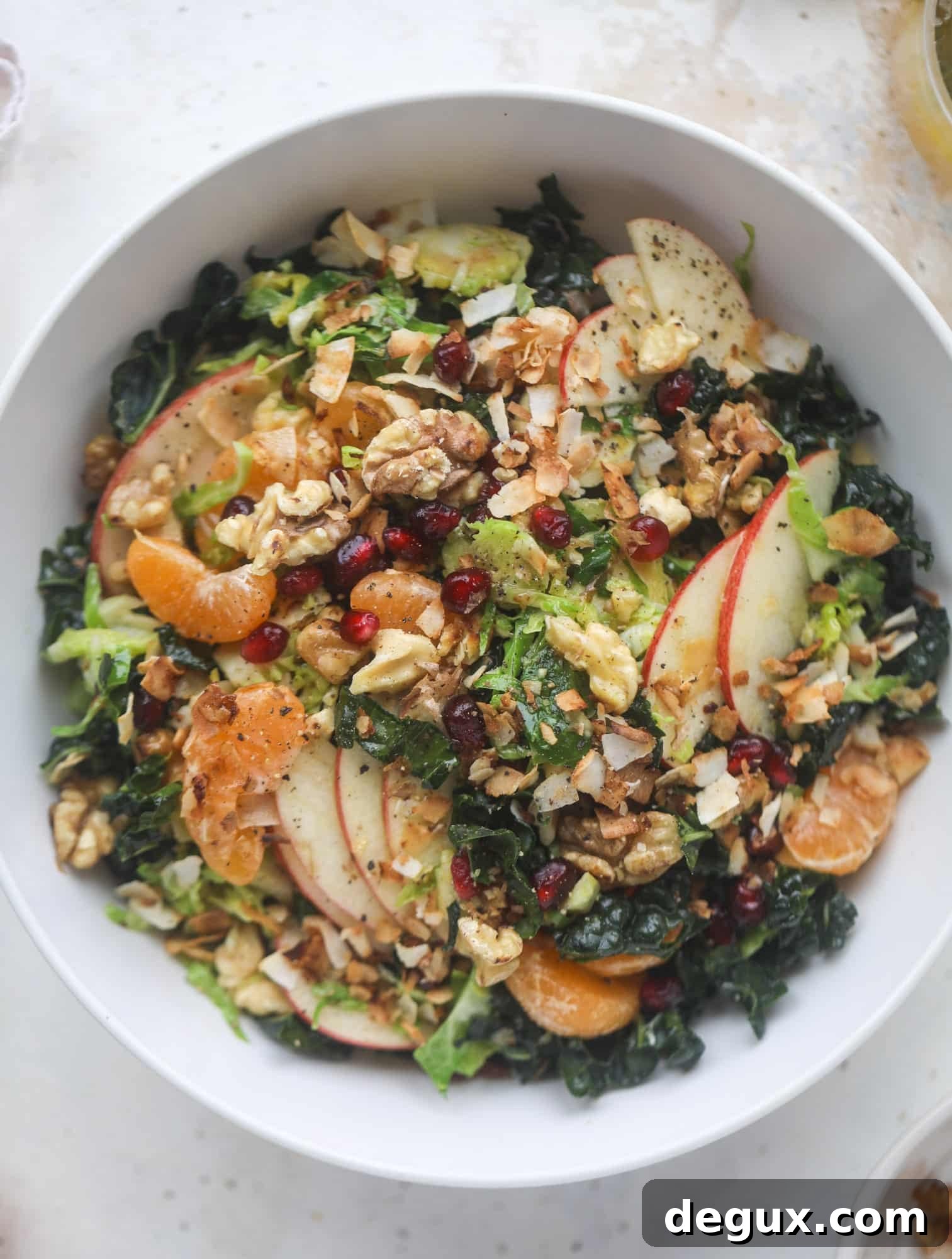 This winter crunch salad is loaded with tons of delicious, crunchy seasonal ingredients. A base of brussels sprouts and kale is topped with sliced apples, satsuma wedges, pomegranate arils, toasted walnuts and savory flaked coconut crunch. Delish! I howsweeteats.com #winter #salad