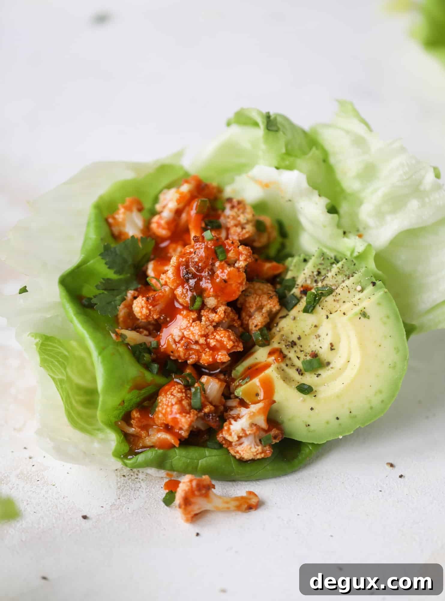 These buffalo cauliflower lettuce wraps are perfect for game day or even a quick weeknight dinner. Roasted cauliflower with buffalo wing sauce, sliced avocado, crumbled blue cheese, scallions, cilantro and chives makes for a flavor explosion! I howsweeteats.com #buffalo #cauliflower