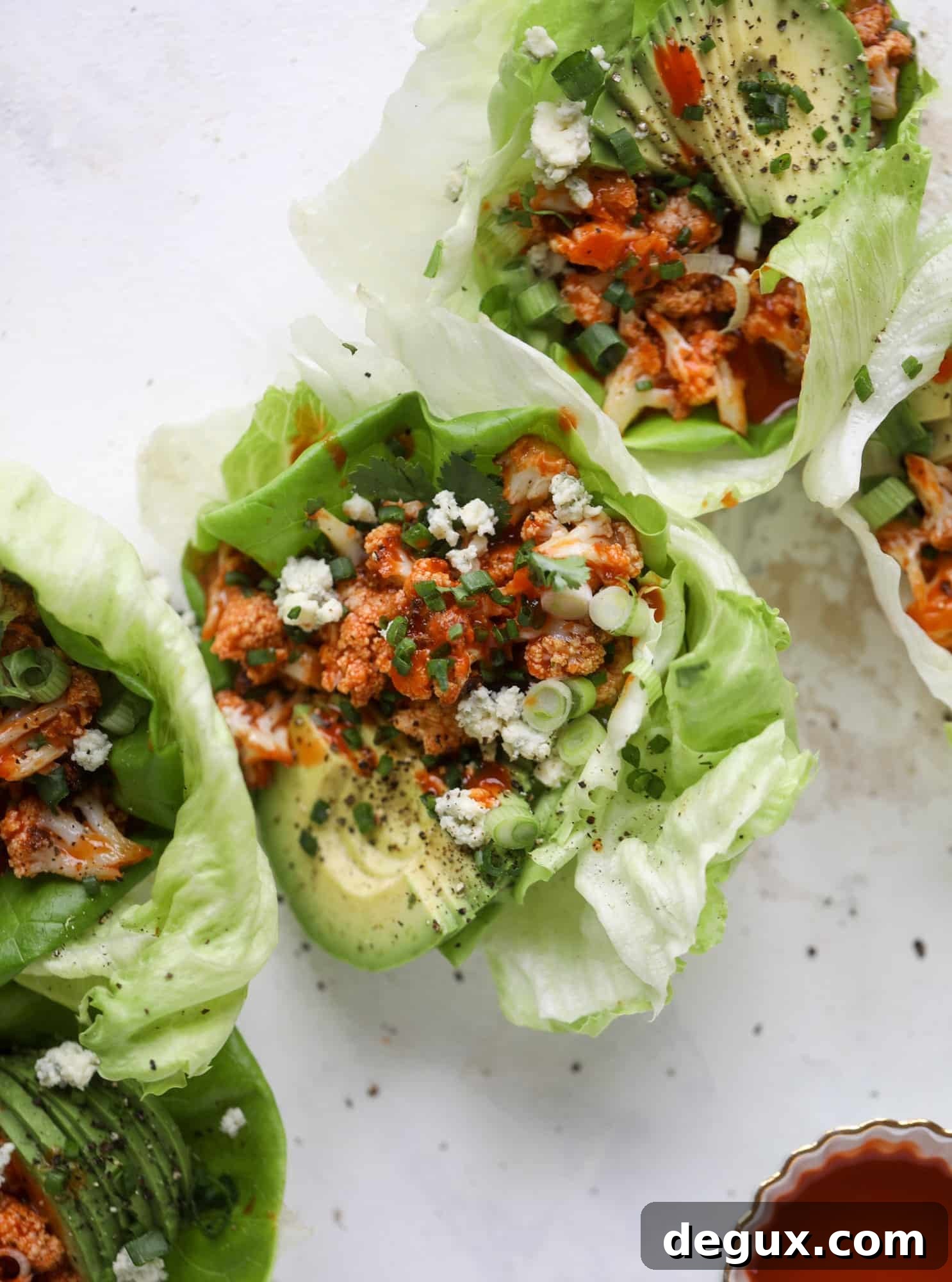 These buffalo cauliflower lettuce wraps are perfect for game day or even a quick weeknight dinner. Roasted cauliflower with buffalo wing sauce, sliced avocado, crumbled blue cheese, scallions, cilantro and chives makes for a flavor explosion! I howsweeteats.com #buffalo #cauliflower