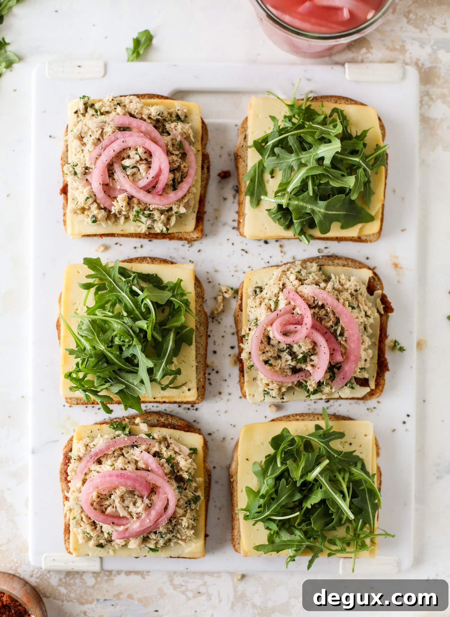 This tuscan tuna melt is a modern way to enjoy a tuna sandwich, with peppery arugula, melty cheese, pickled onions and sun dried tomato spread! I howsweeteats.com #tuna #melt
