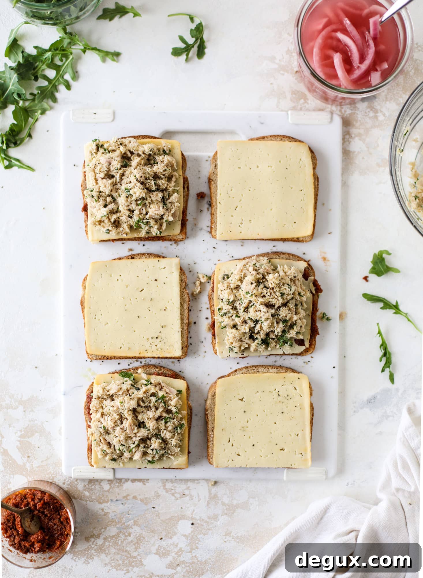 This tuscan tuna melt is a modern way to enjoy a tuna sandwich, with peppery arugula, melty cheese, pickled onions and sun dried tomato spread! I howsweeteats.com #tuna #melt