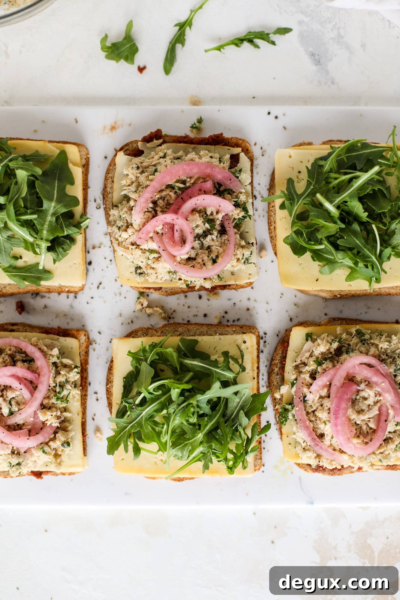 This tuscan tuna melt is a modern way to enjoy a tuna sandwich, with peppery arugula, melty cheese, pickled onions and sun dried tomato spread! I howsweeteats.com #tuna #melt