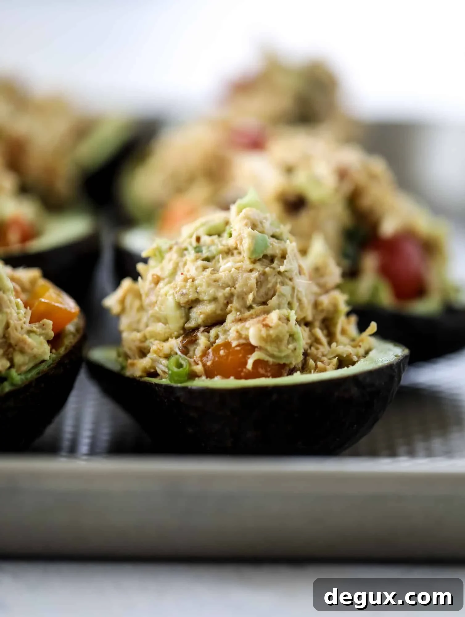 These baked avocados are stuffed with a cheesy chicken mixture and drizzled with sriracha yogurt sauce! Super delicious and an easy weeknight meal.
