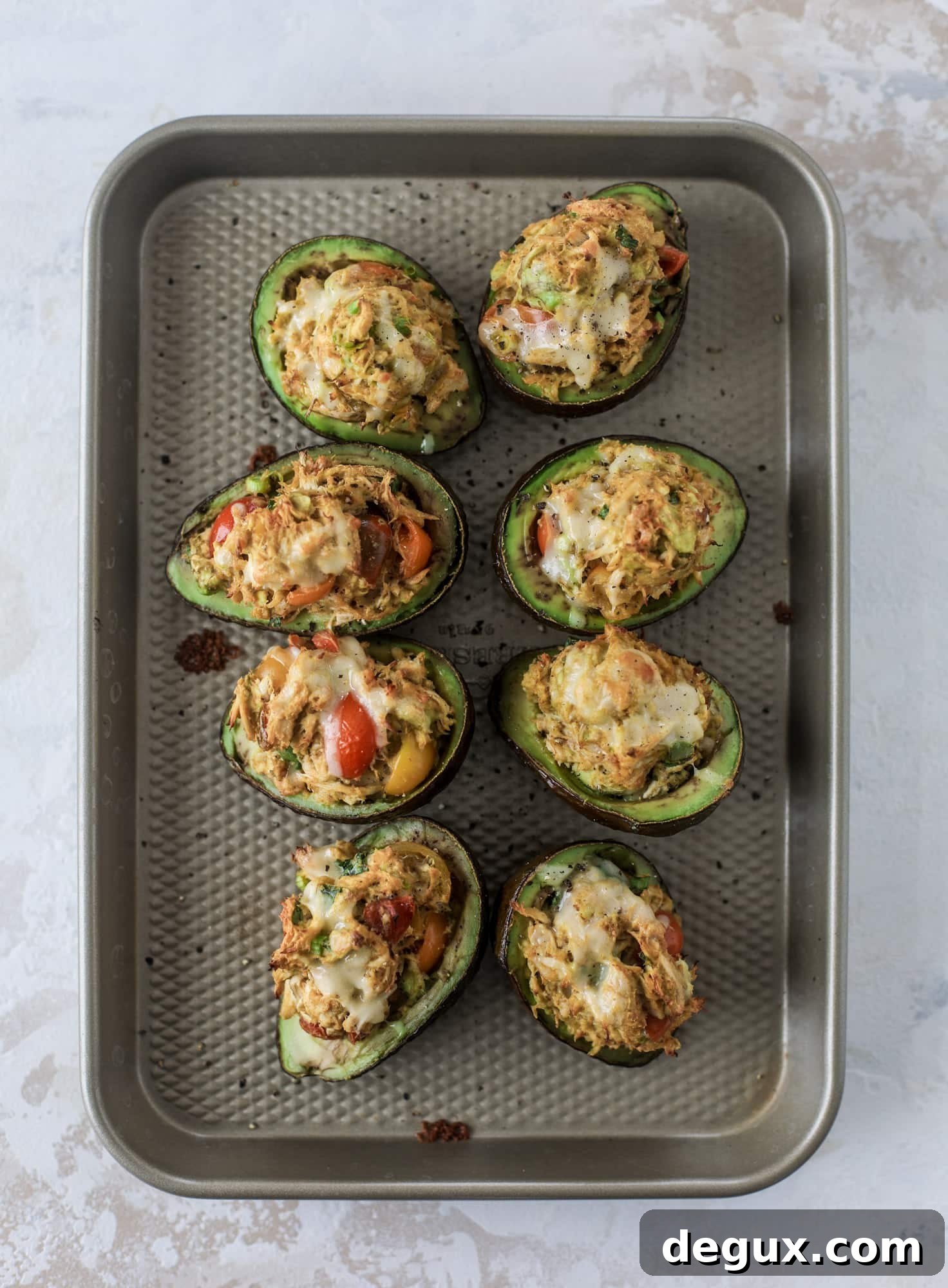 These baked avocados are stuffed with a cheesy chicken mixture and drizzled with sriracha yogurt sauce! Super delicious and an easy weeknight meal.