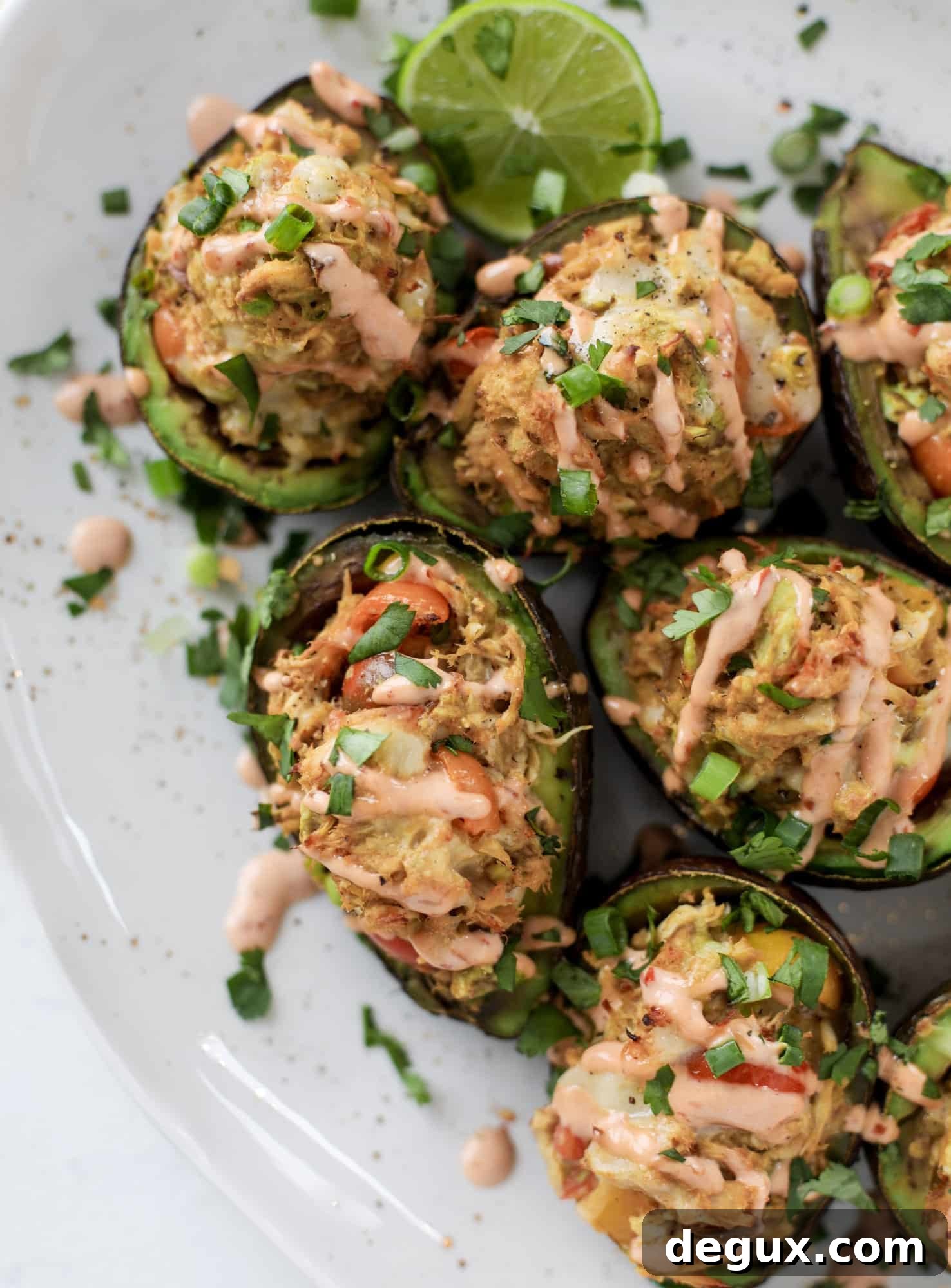 These baked avocados are stuffed with a cheesy chicken mixture and drizzled with sriracha yogurt sauce! Super delicious and an easy weeknight meal.