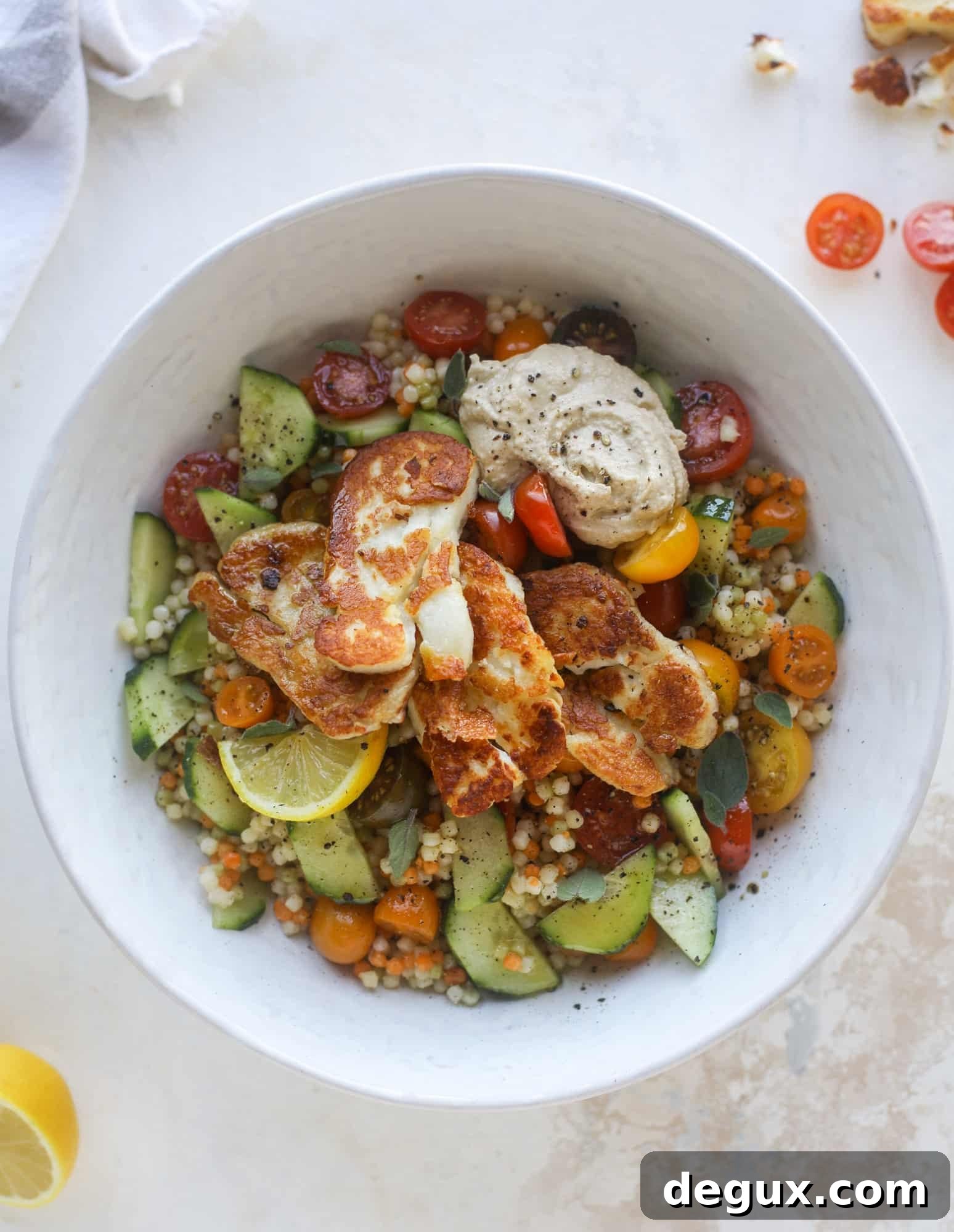 I am obsessed with these haulloumi hummus bowls for lunch or dinner. Couscous, veggies, crispy halloumi cheese and hummus with lots of lemon. Yum! I howsweeteats.com #halloumi #hummus