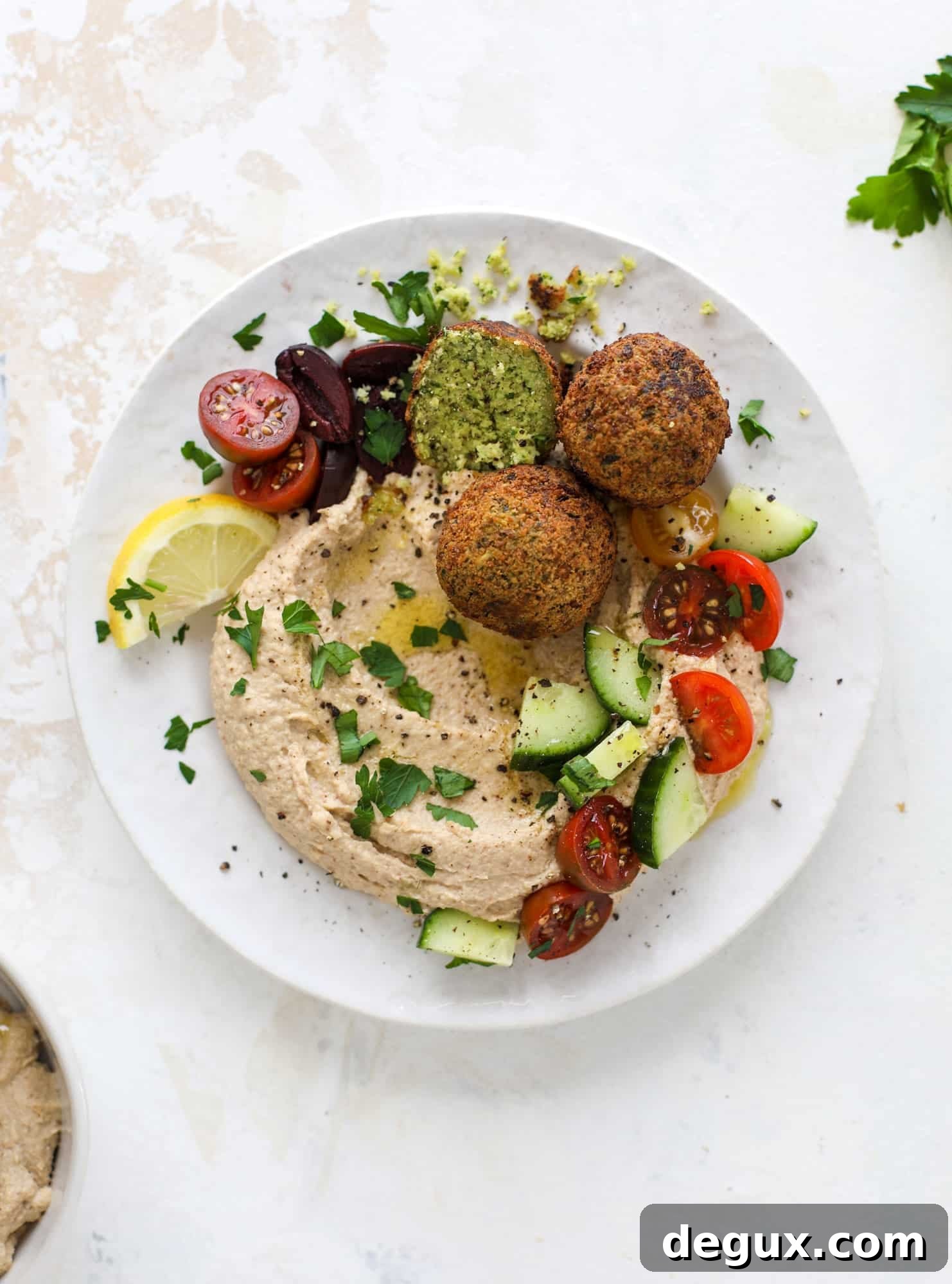 Green Goddess Falafel with Creamy Cauliflower Hummus 2 Green goddess falafel is hearty and flavorful, served over the creamiest cauliflower hummus, with tomatoes, olive, cucumbers and feta. Yum! I howsweeteats.com #falafel #cauliflowerhummus
