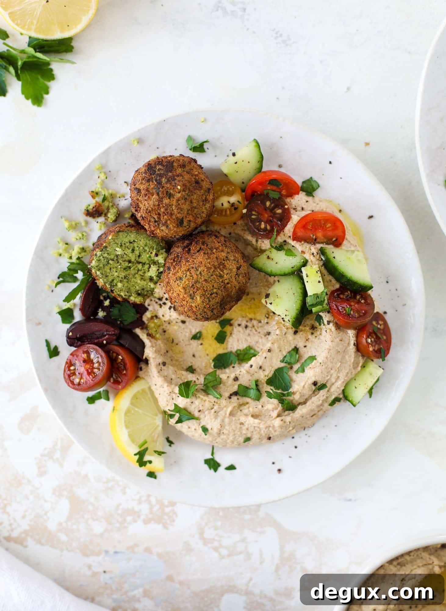 Green Goddess Falafel with Creamy Cauliflower Hummus 10 Green goddess falafel is hearty and flavorful, served over the creamiest cauliflower hummus, with tomatoes, olive, cucumbers and feta. Yum! I howsweeteats.com #falafel #cauliflowerhummus