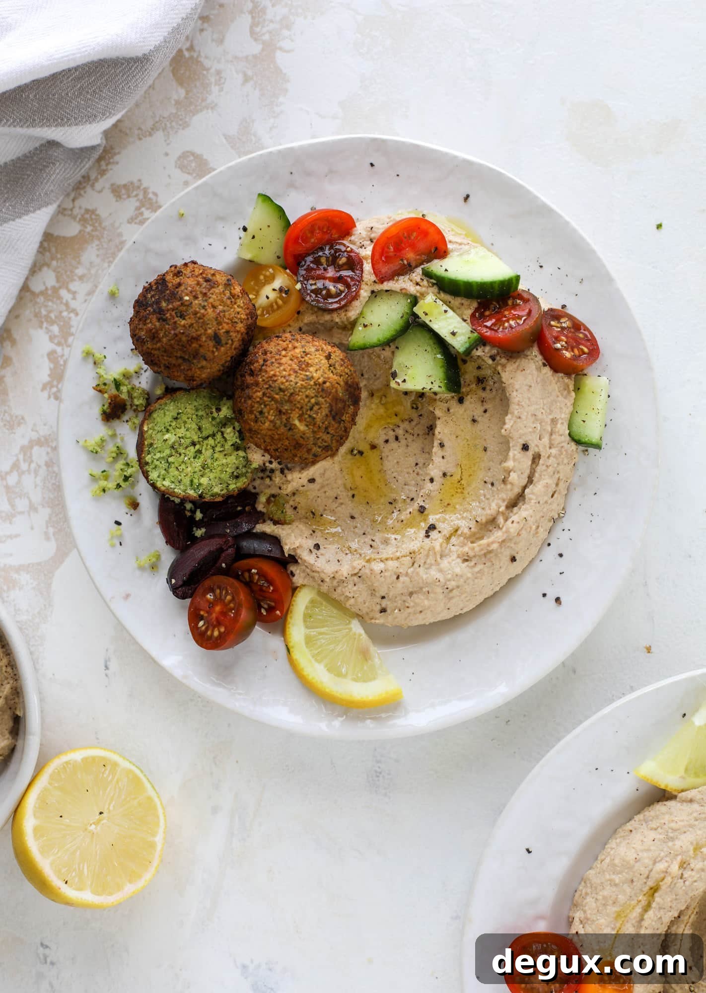 Green Goddess Falafel with Creamy Cauliflower Hummus 7 Green goddess falafel is hearty and flavorful, served over the creamiest cauliflower hummus, with tomatoes, olive, cucumbers and feta. Yum! I howsweeteats.com #falafel #cauliflowerhummus