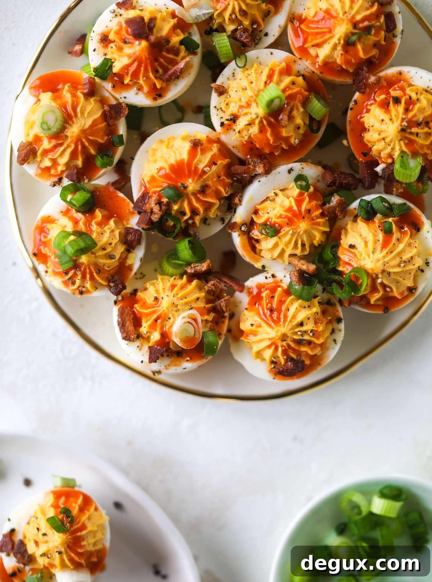 Buffalo deviled eggs are kicked-up deviled eggs! Made with goat cheese filling and served with buffalo wing sauce, crispy bacon and sliced scallions. I howsweeteats.com #deviledeggs #buffalo