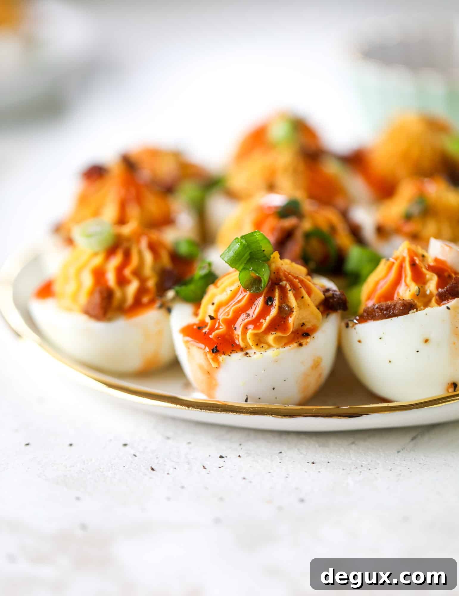 Buffalo deviled eggs are kicked-up deviled eggs! Made with goat cheese filling and served with buffalo wing sauce, crispy bacon and sliced scallions. I howsweeteats.com #deviledeggs #buffalo