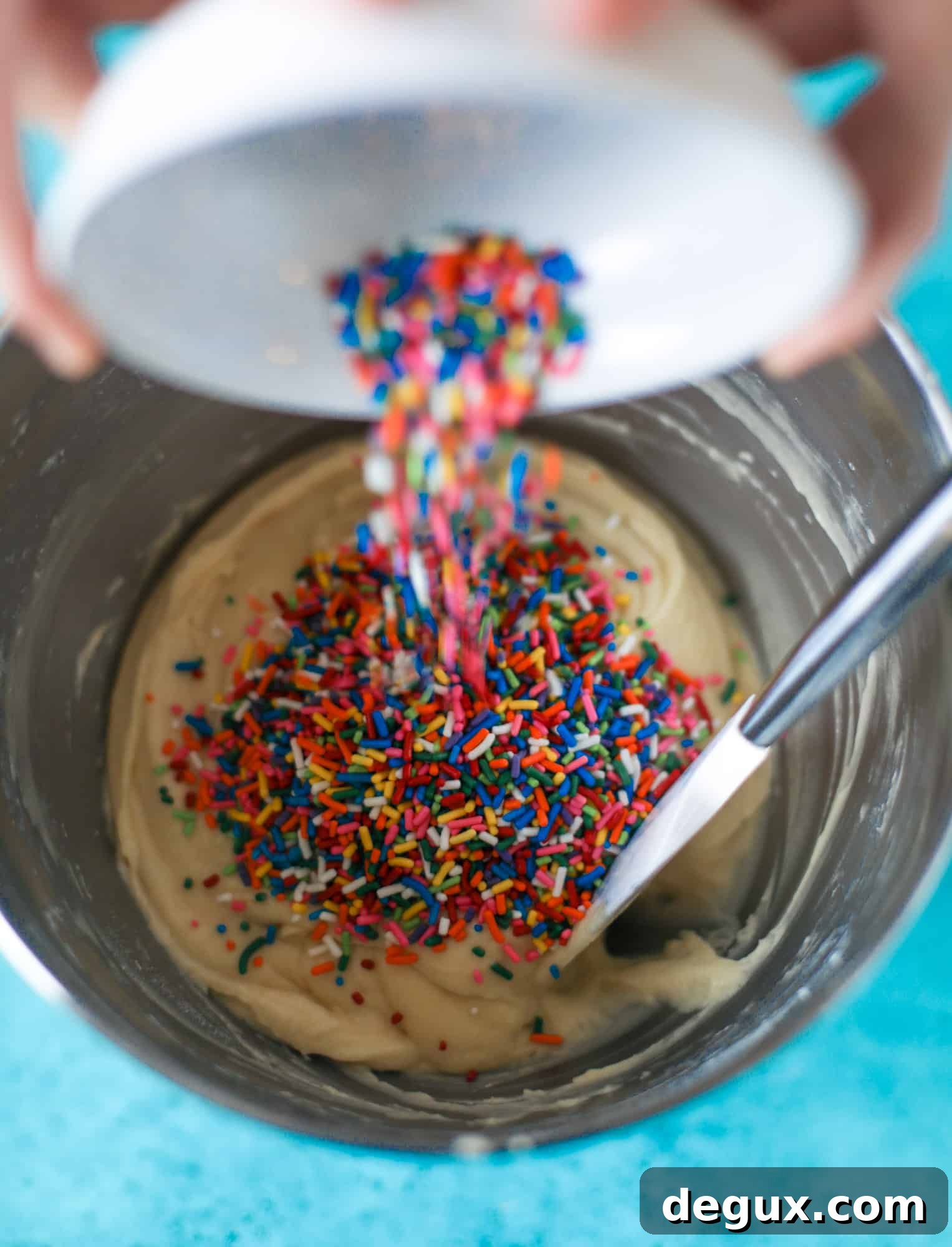 pouring rainbow sprinkles into cake batter