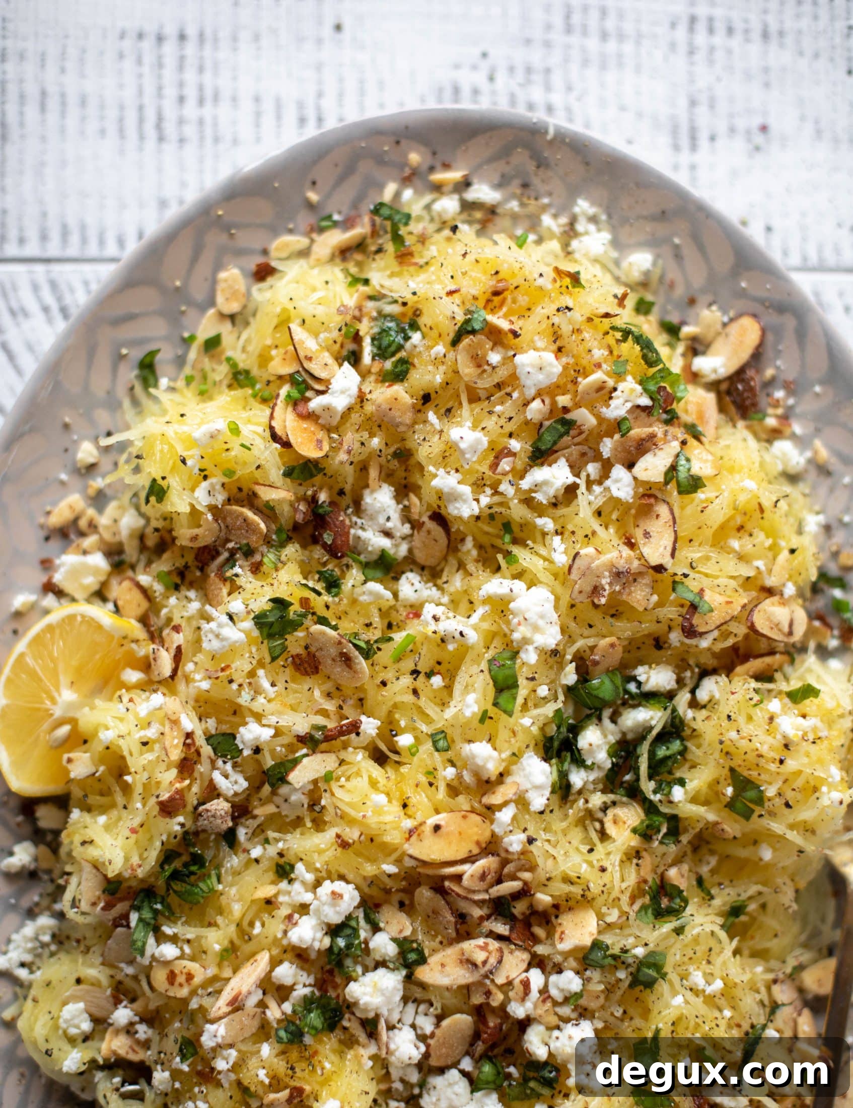 This lemon spaghetti squash is tossed in a lemon garlic butter and topped with feta, sliced toasted almonds and fresh herbs. It's delicious! 