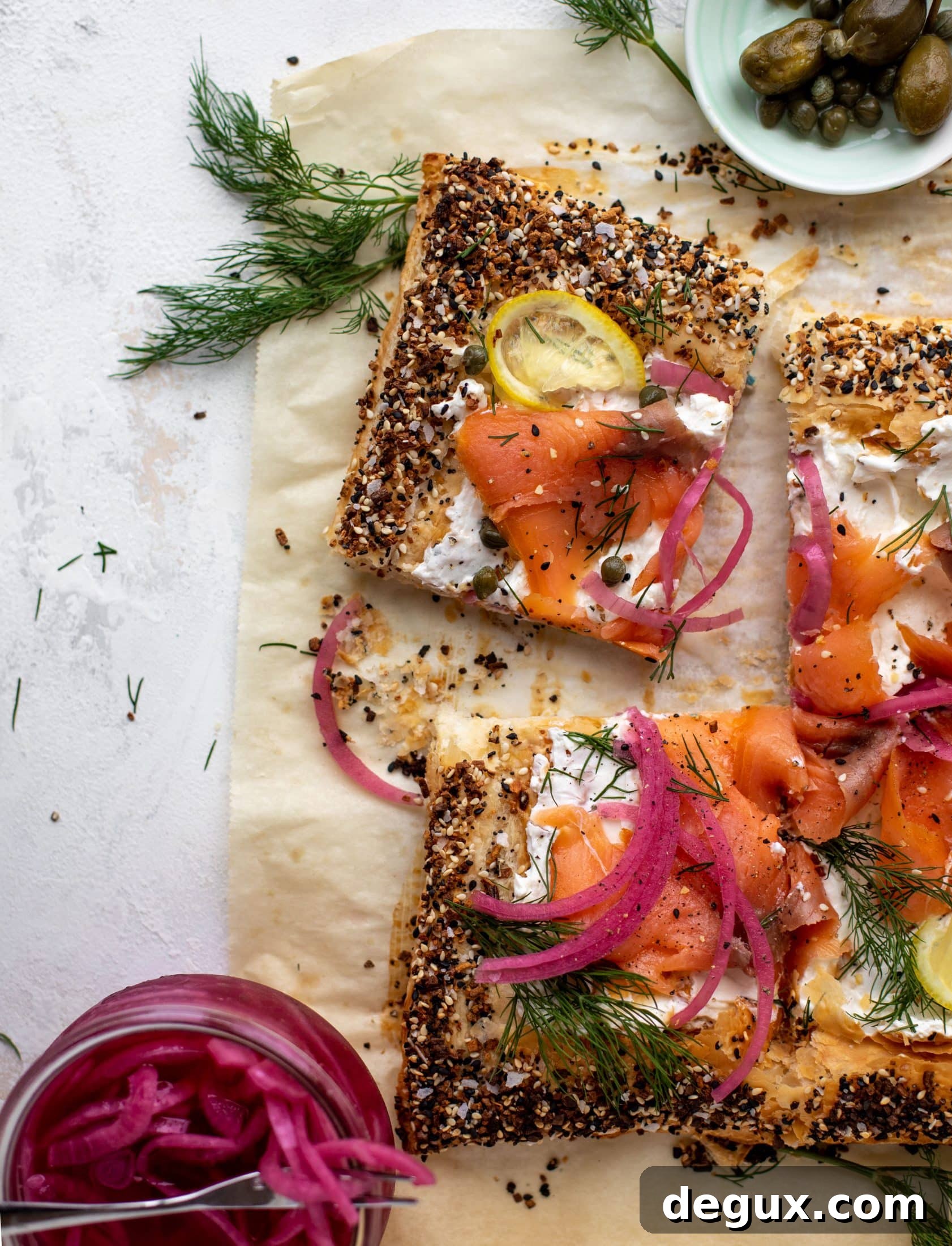 This everything smoked salmon tart is perfect for brunch! Puff pastry sprinkled with everything seasoning, slathered in cream cheese and topped with salmon.