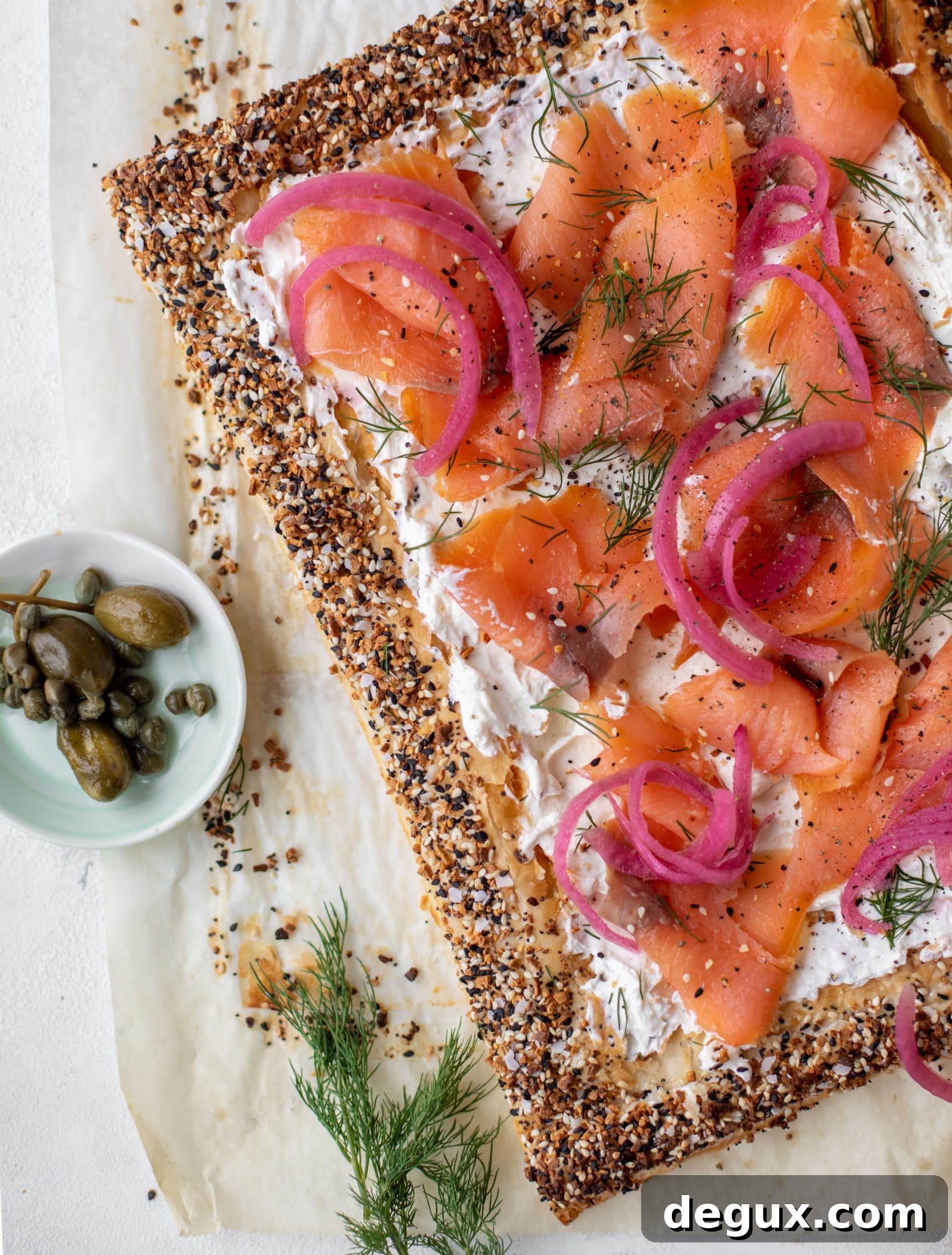 This everything smoked salmon tart is perfect for brunch! Puff pastry sprinkled with everything seasoning, slathered in cream cheese and topped with salmon.